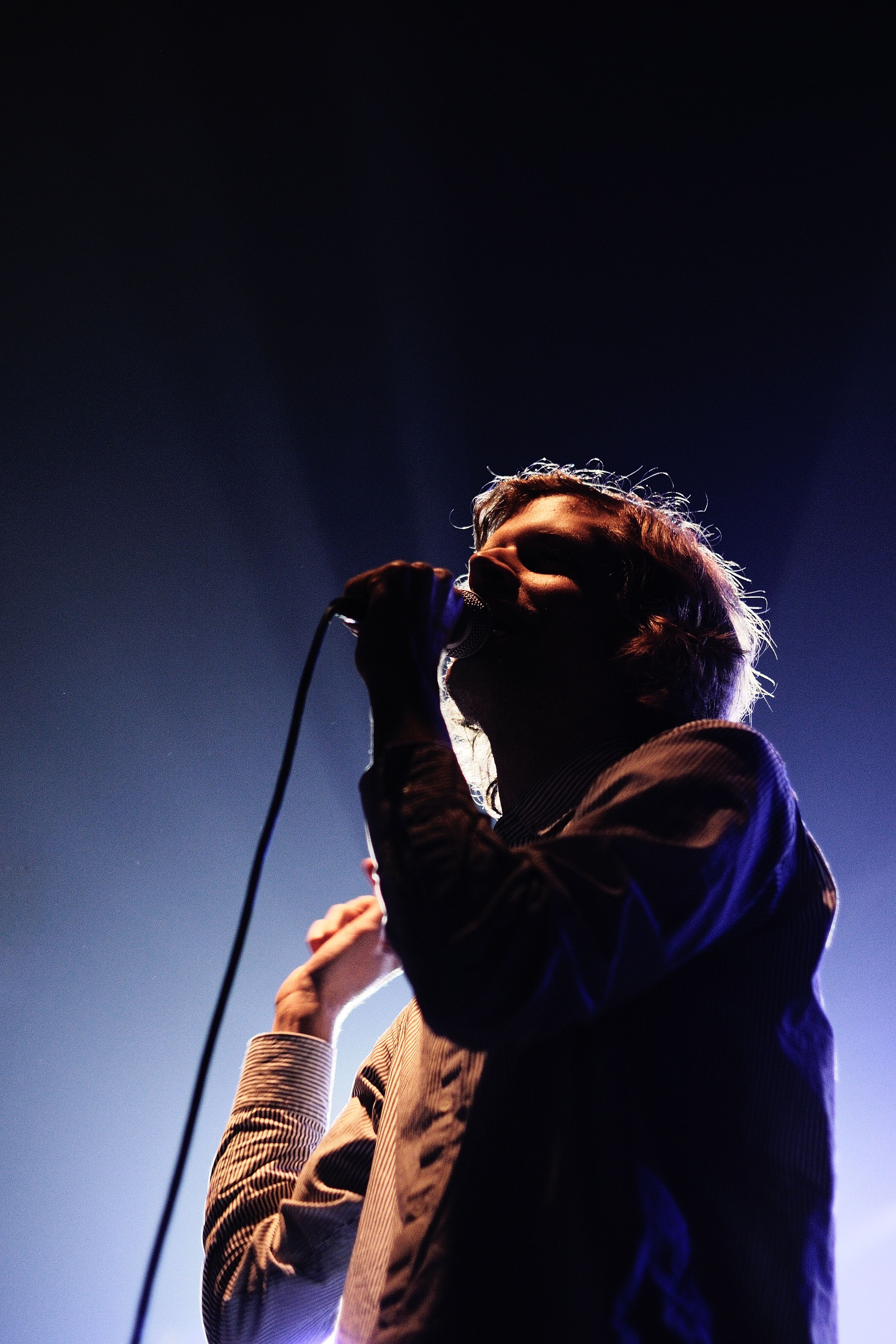 A person singing into a microphone at a concert in Bergen, Fjord Norway