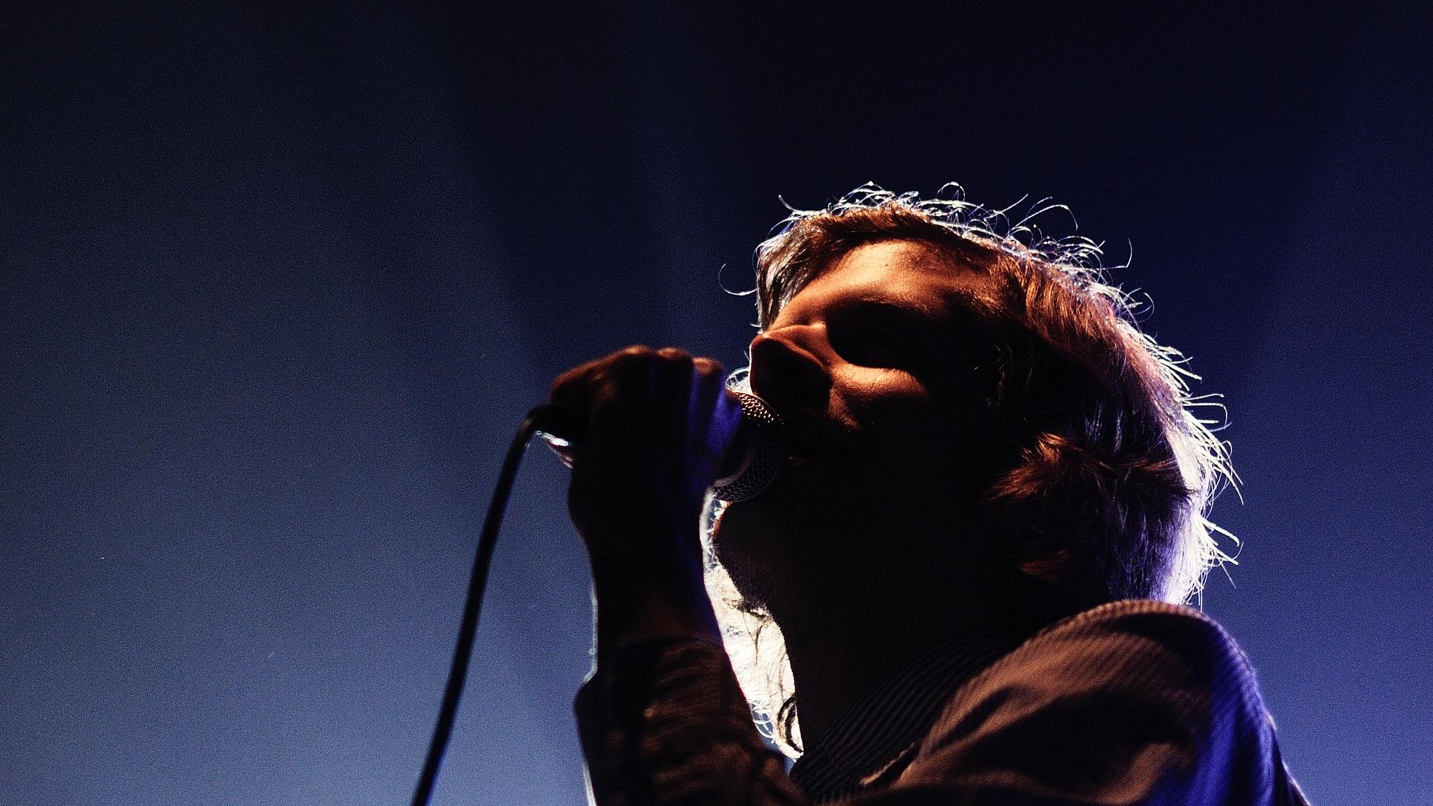 A person singing into a microphone at a concert in Bergen, Fjord Norway