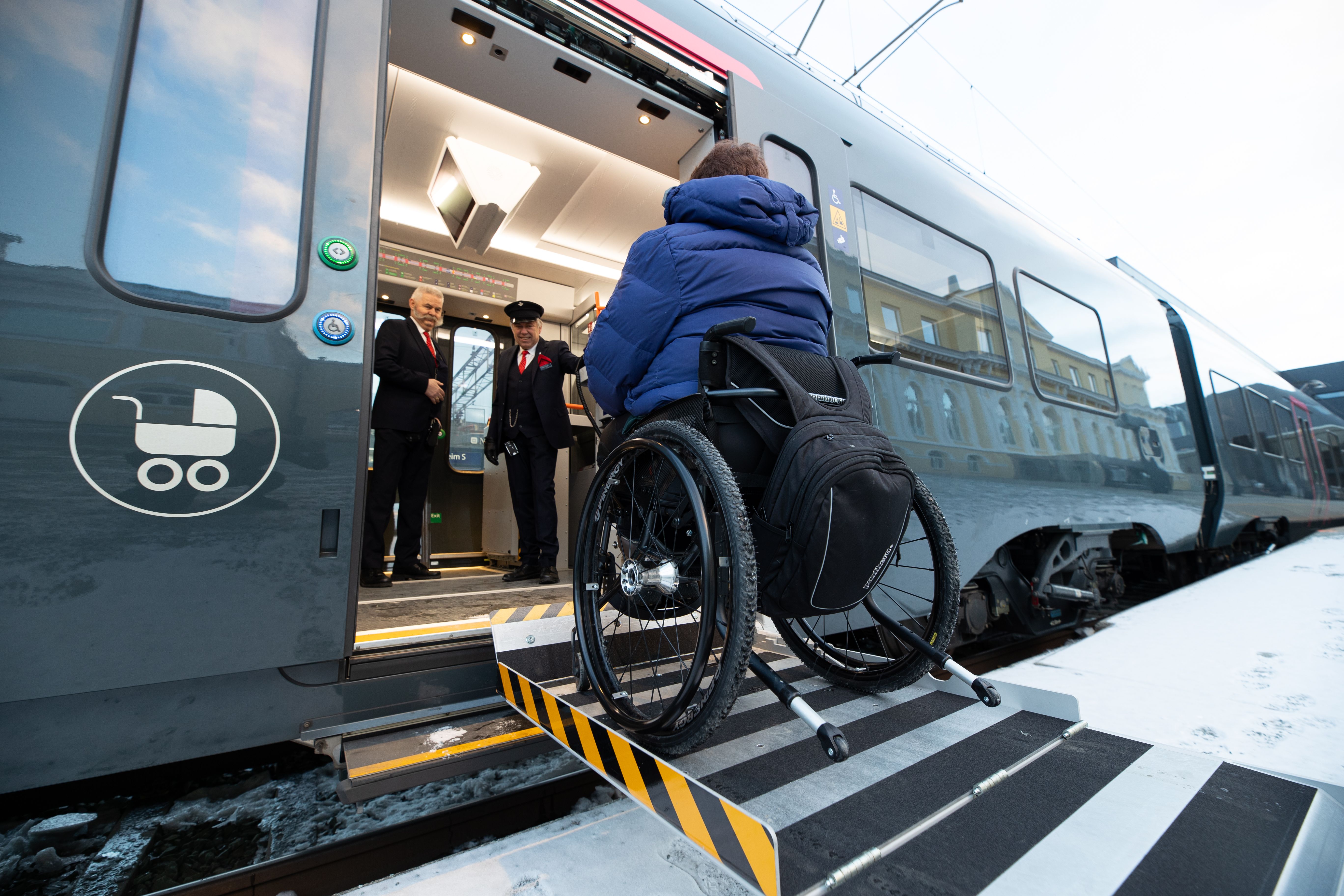 Person entrer toget med elektrisk rullestol via rampe