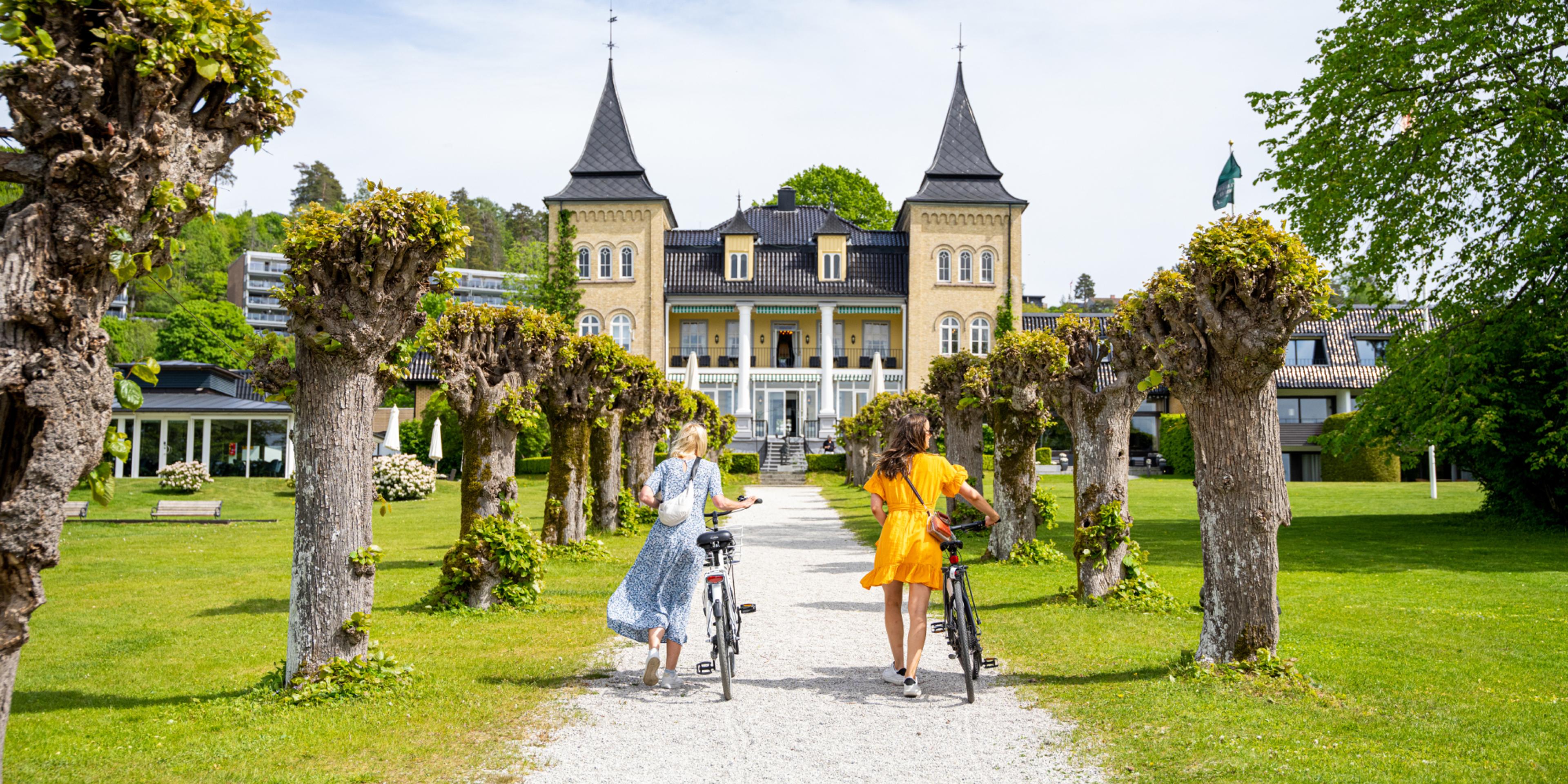 Two people walking with bikes to Refsnes Gods at Jeløya in Moss
