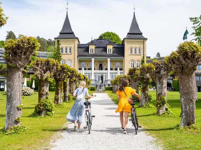 Two people walking with bikes to Refsnes Gods at Jeløya in Moss