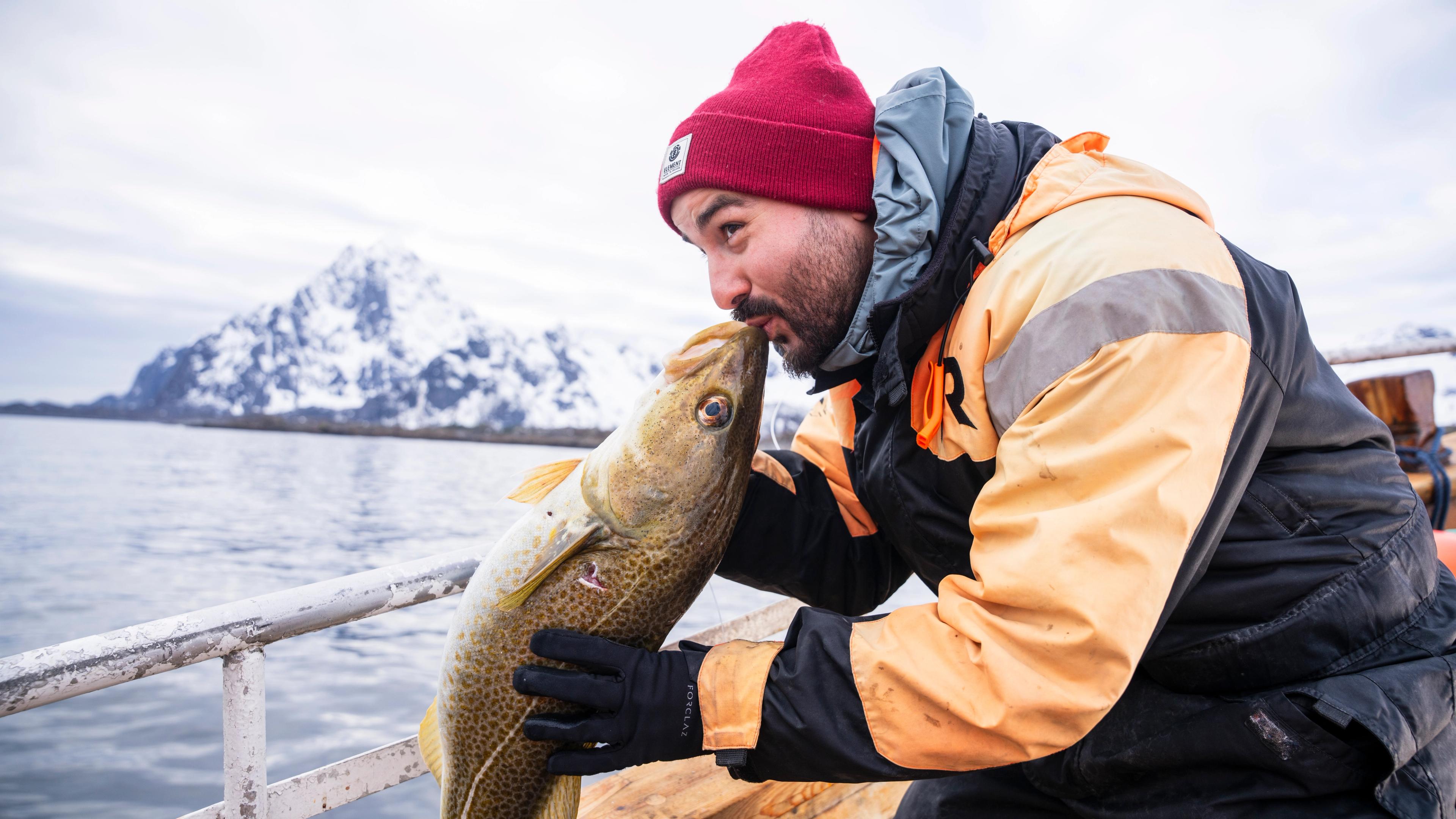 Man kissing an Arctic cod on a fishing trip