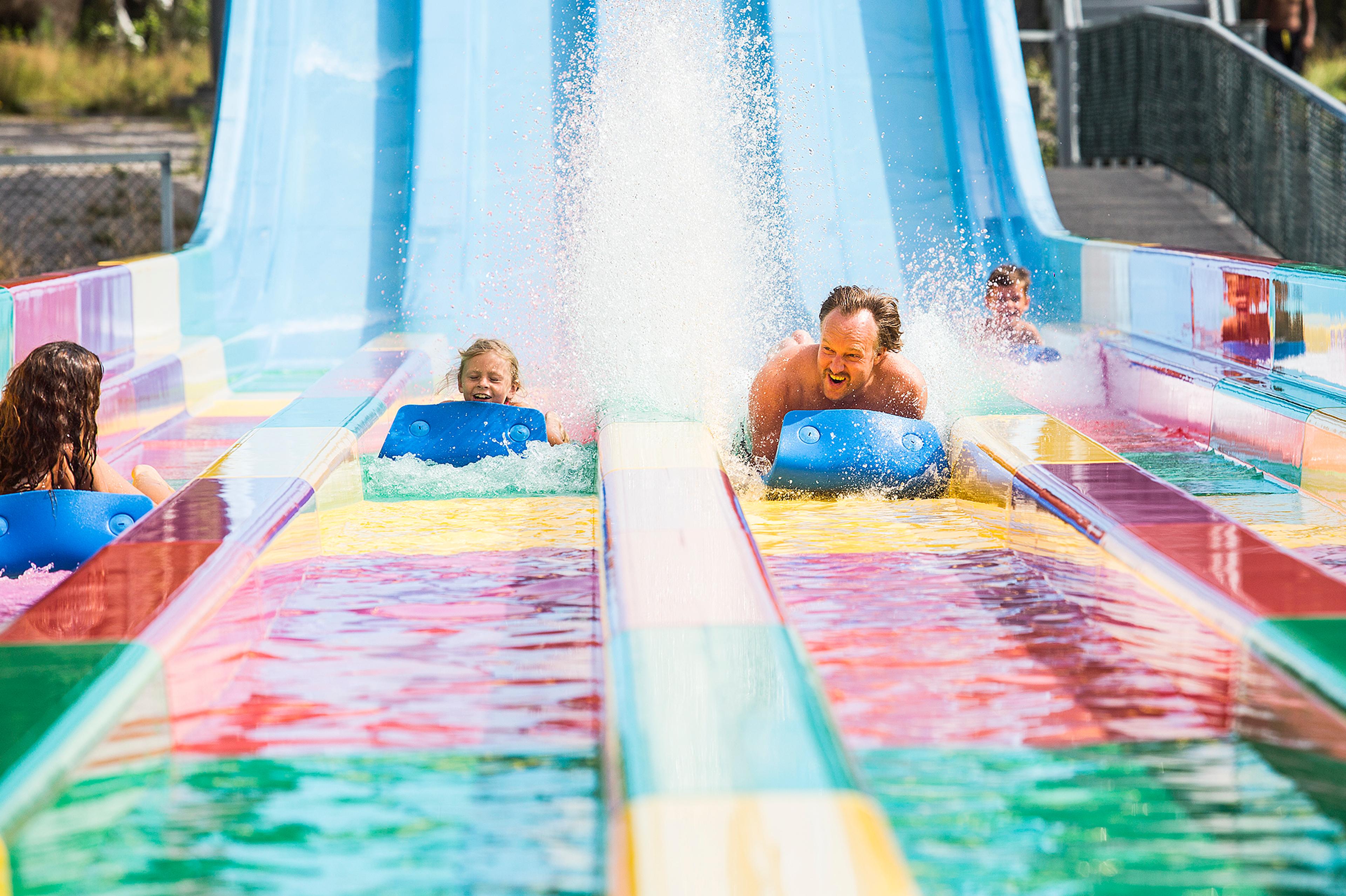 a child and an adult slide down a slide in Bø Sommarland, Norway