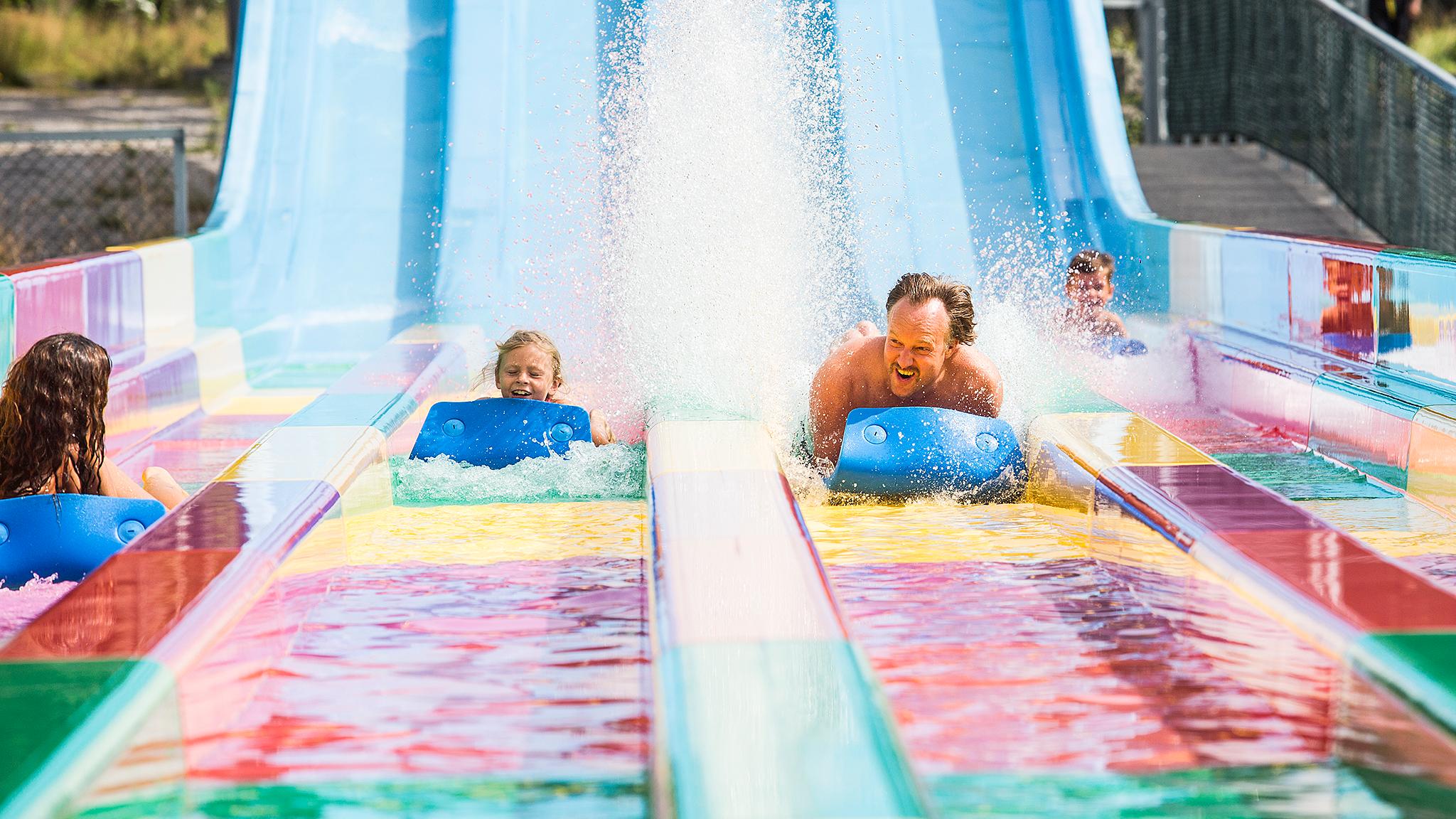 a child and an adult slide down a slide in Bø Sommarland, Norway