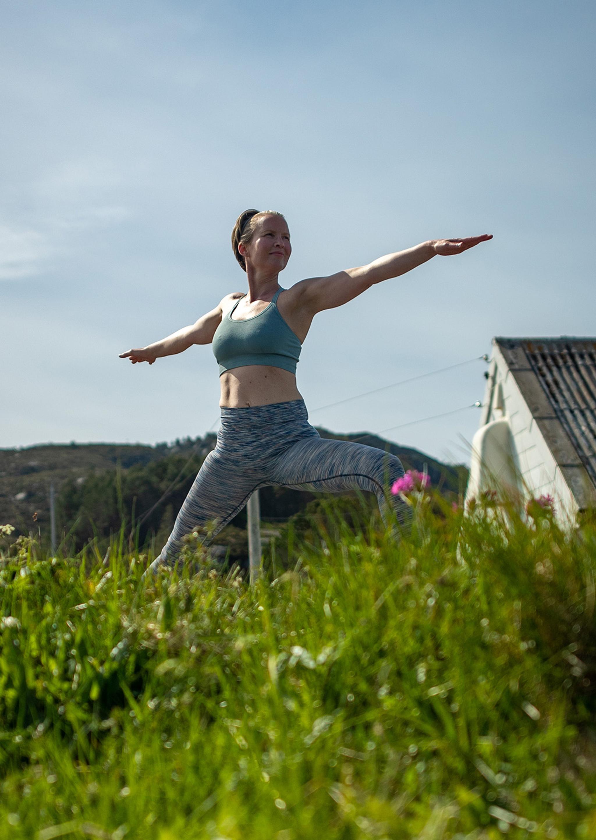 En dame, Rutt-Lovise gjør yoga, en "warrior" posering på Skongenes fyr