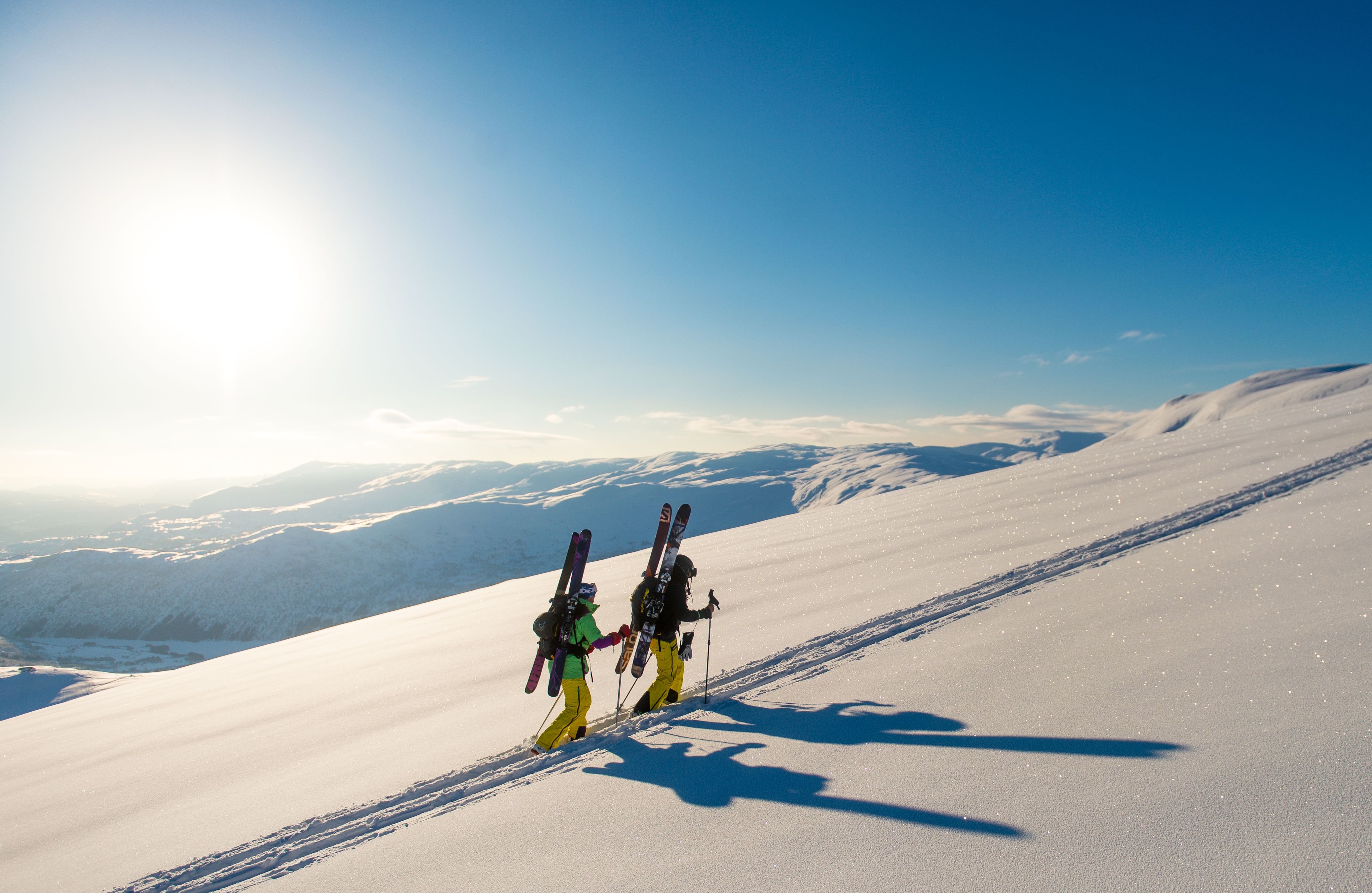 Two people are walking with their skis on their back towards a top in Myrkdalen, Fjord Norway