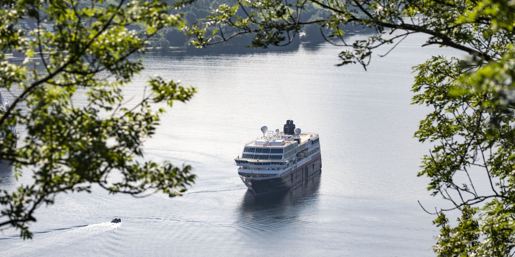 Hurtigruten seen through branches in Geiranger