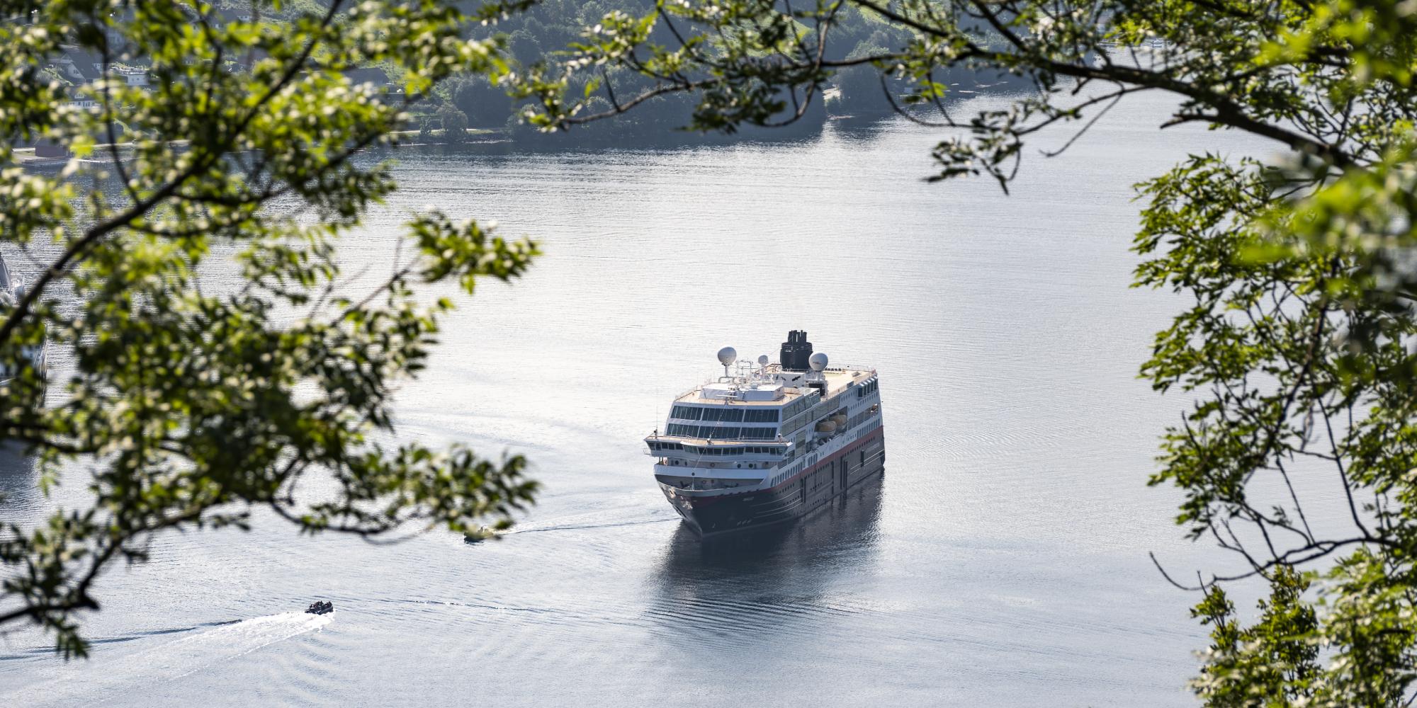 Hurtigruten seen through branches in Geiranger