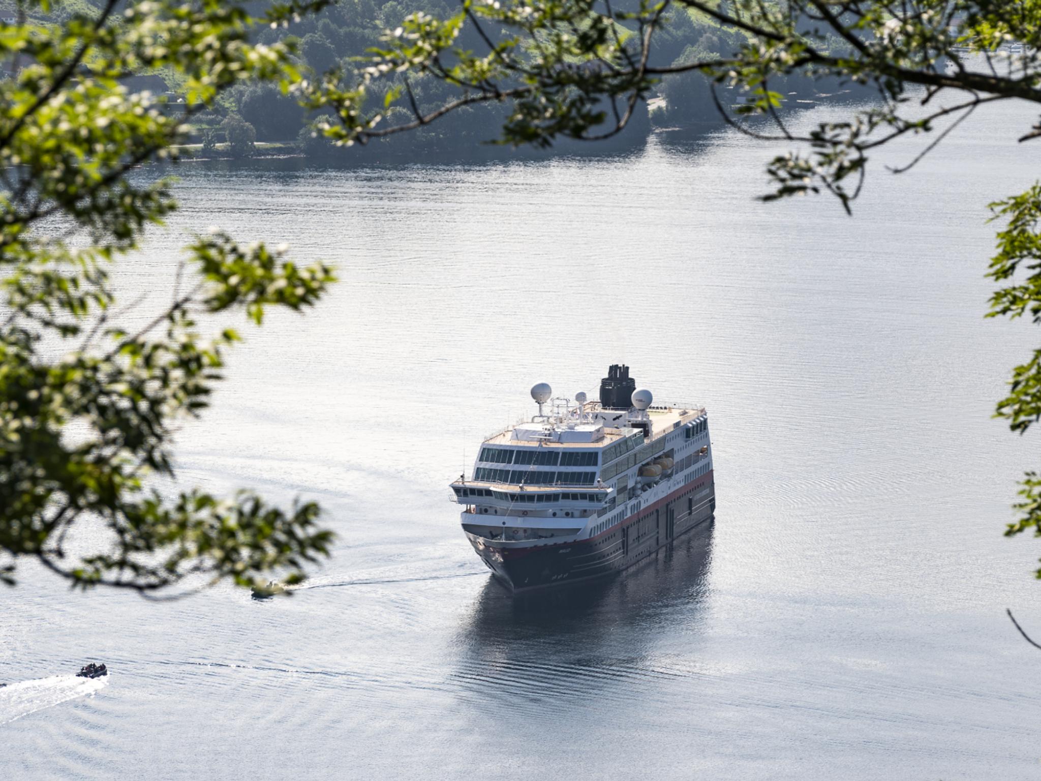 Hurtigruten seen through branches in Geiranger