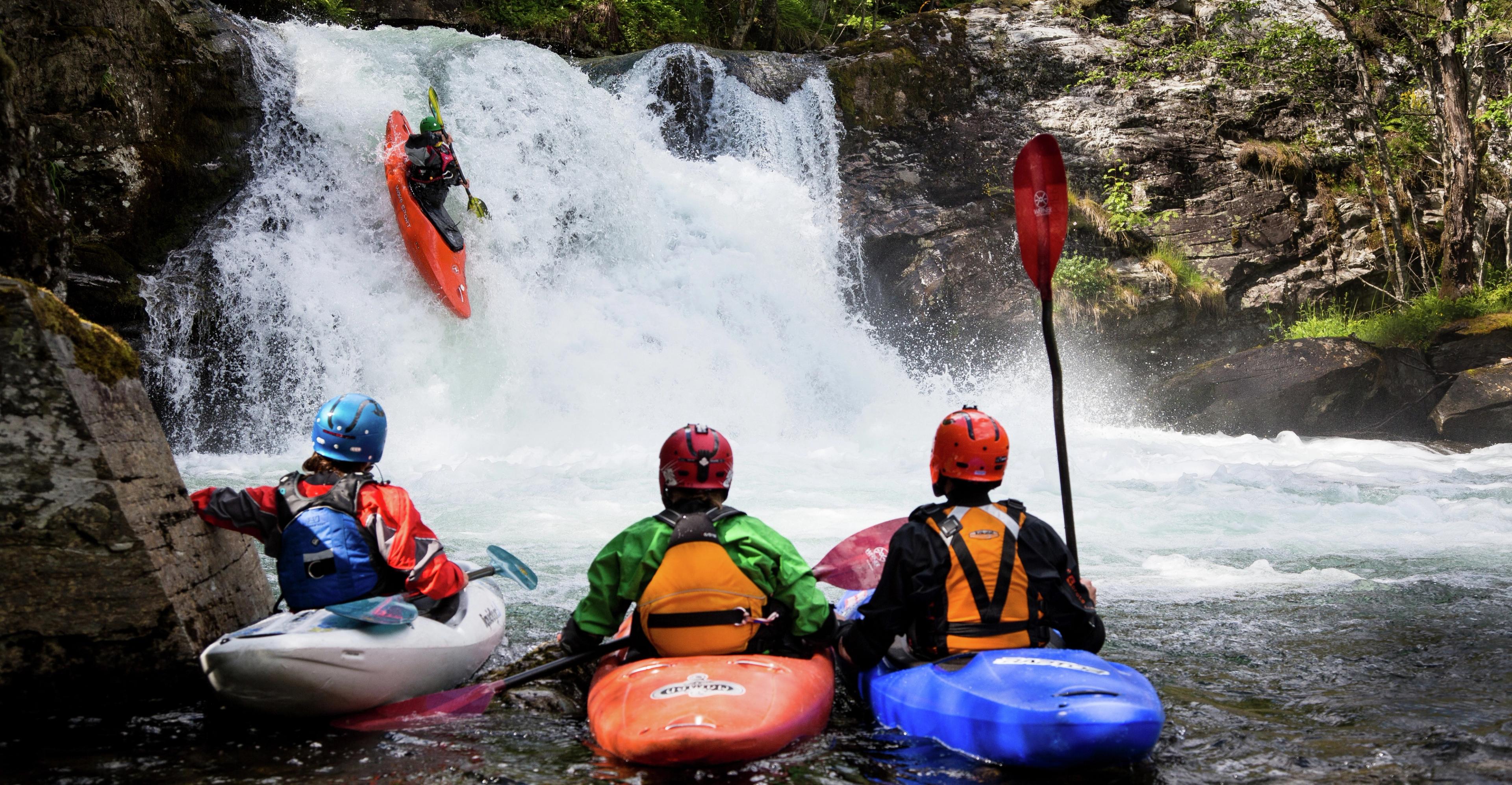 People kayaking on a small waterfall