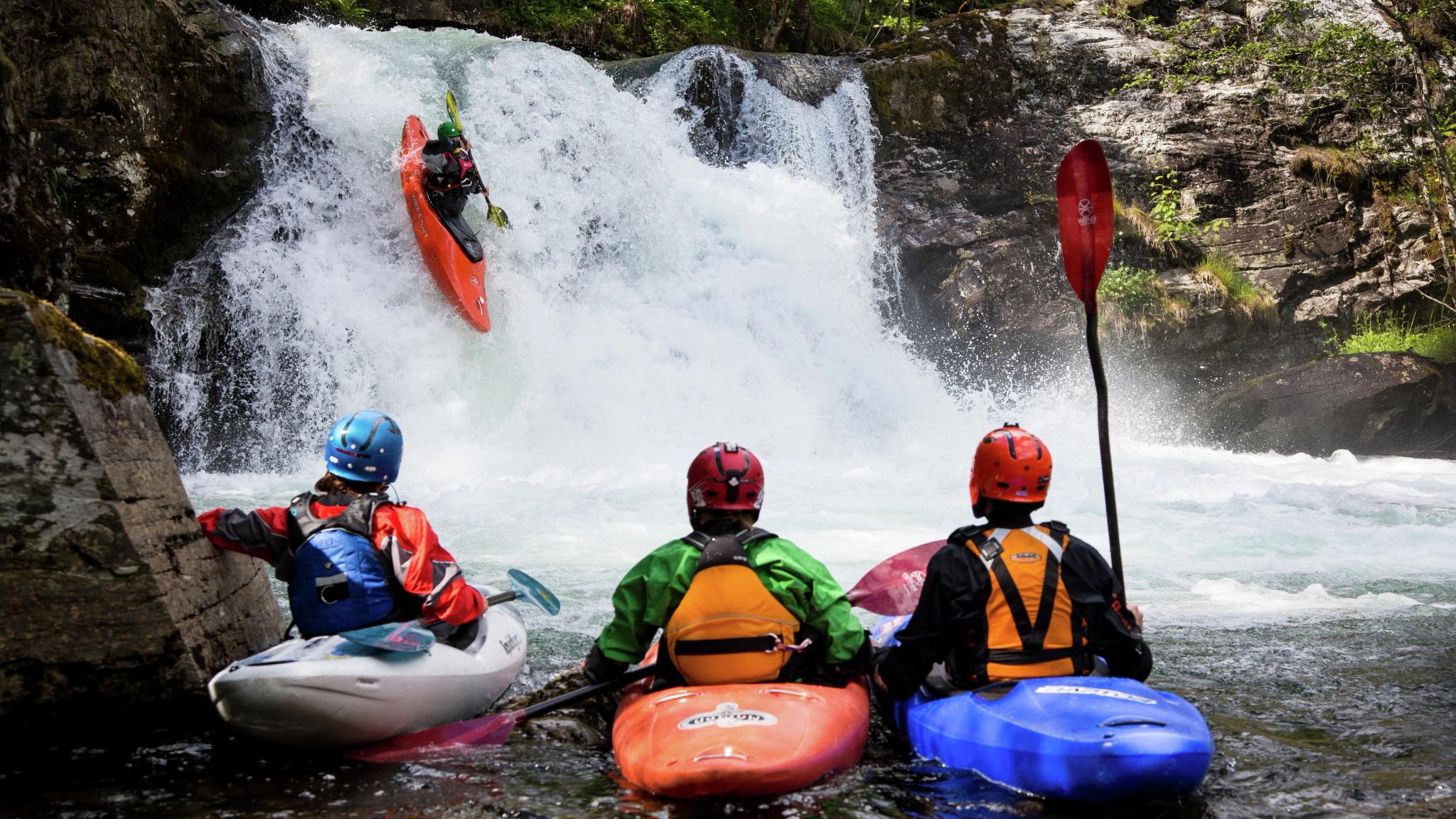 People kayaking on a small waterfall