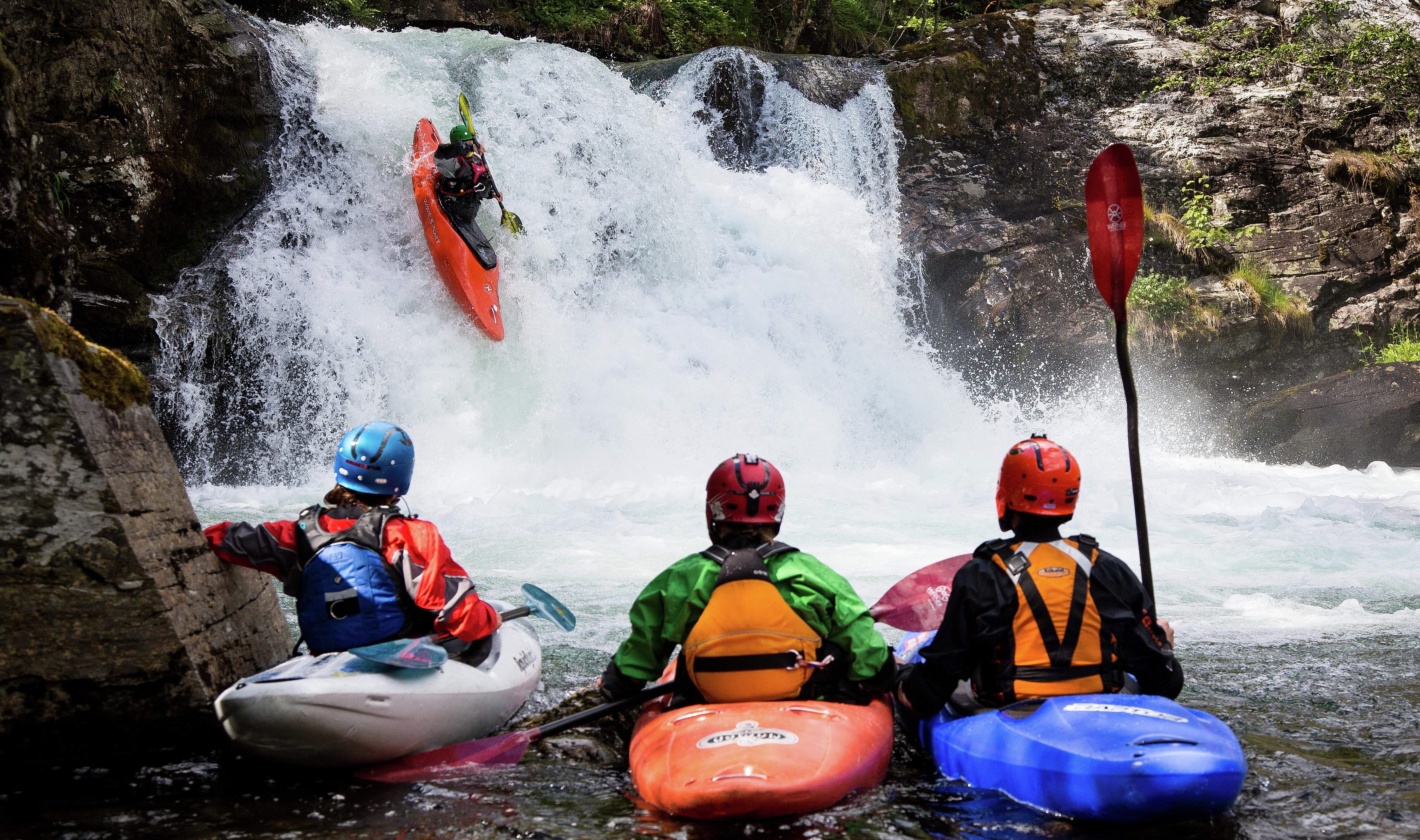 People kayaking on a small waterfall