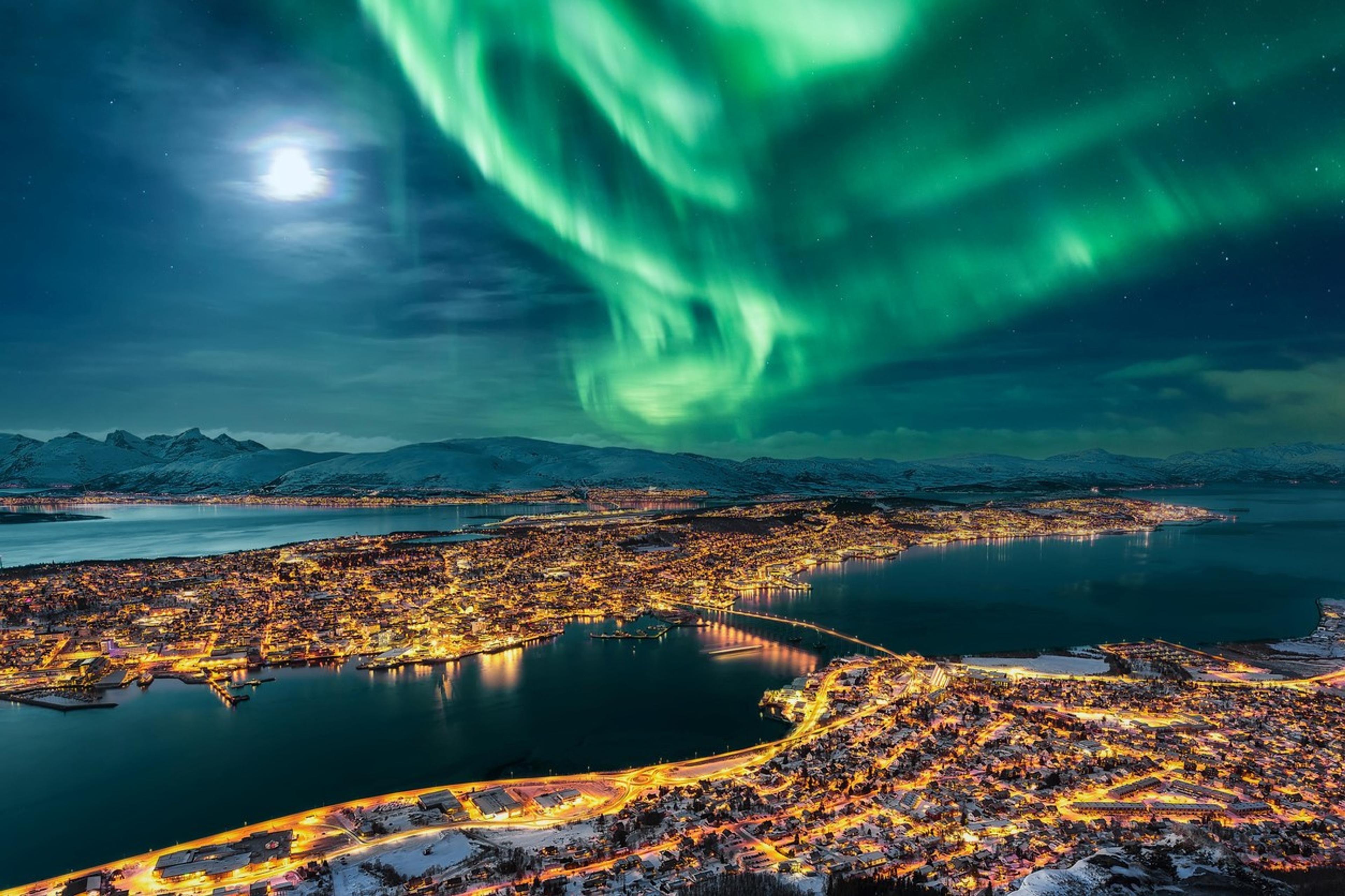 Aurora over coastal city Tromsø at night with full moon.