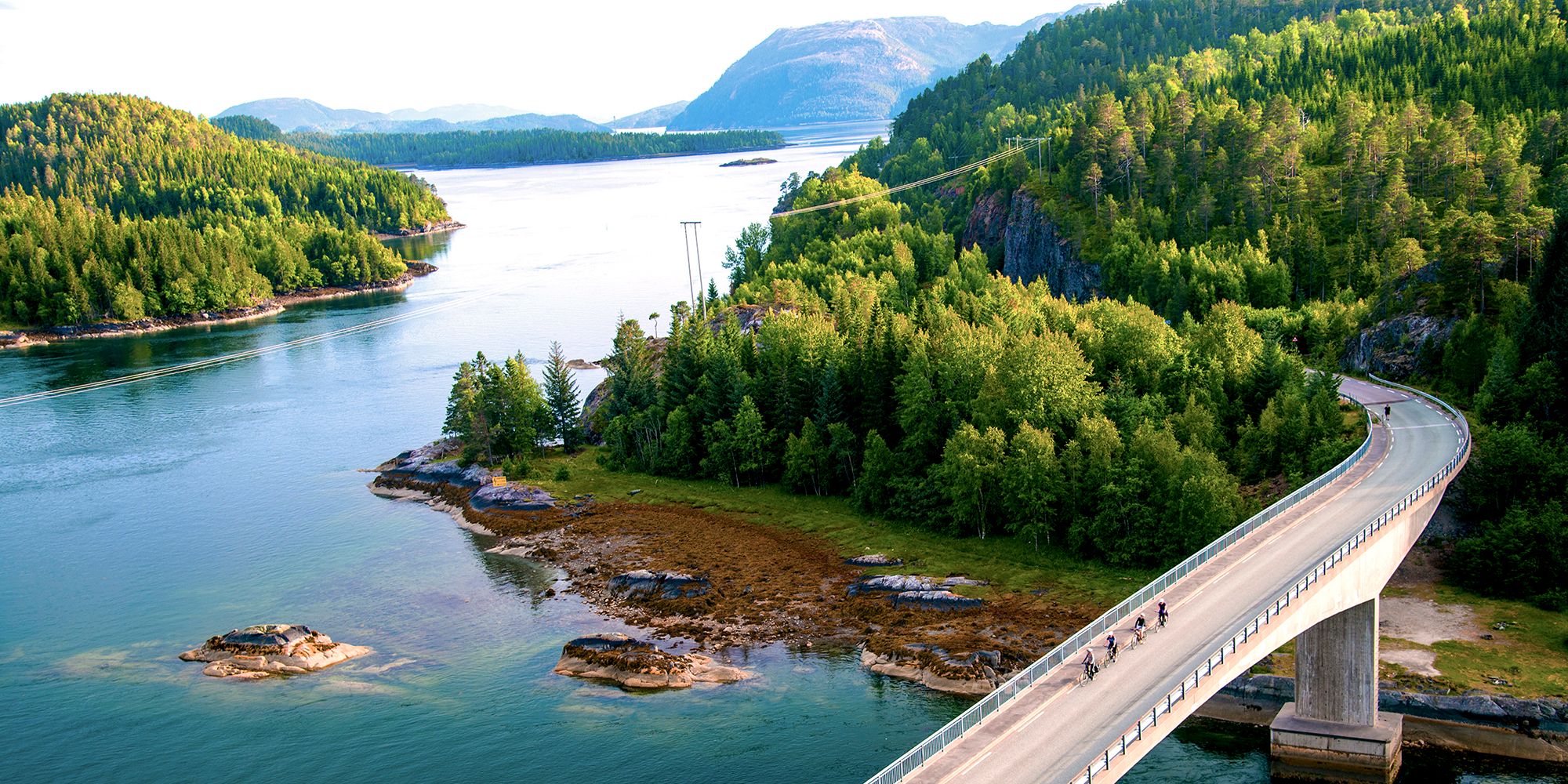 Ciclisti su un ponte lungo la costa Namdalskysten nel Trøndelag in una soleggiata giornata estiva