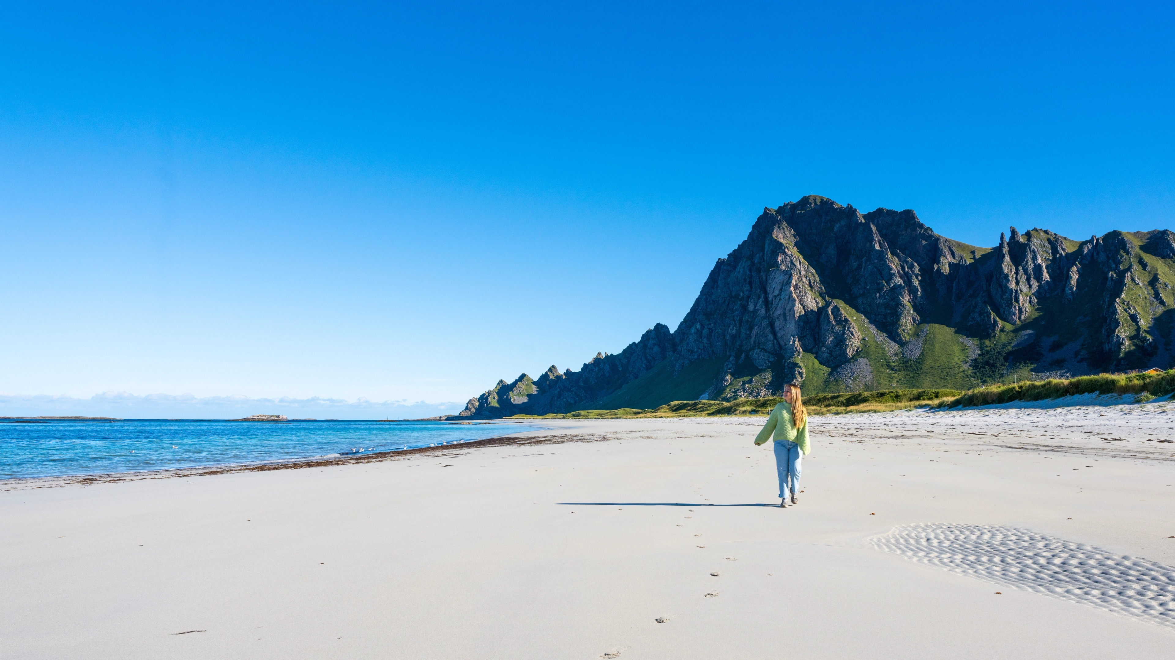A woman walking along Bleikstranda, Bleik beach on Andøya