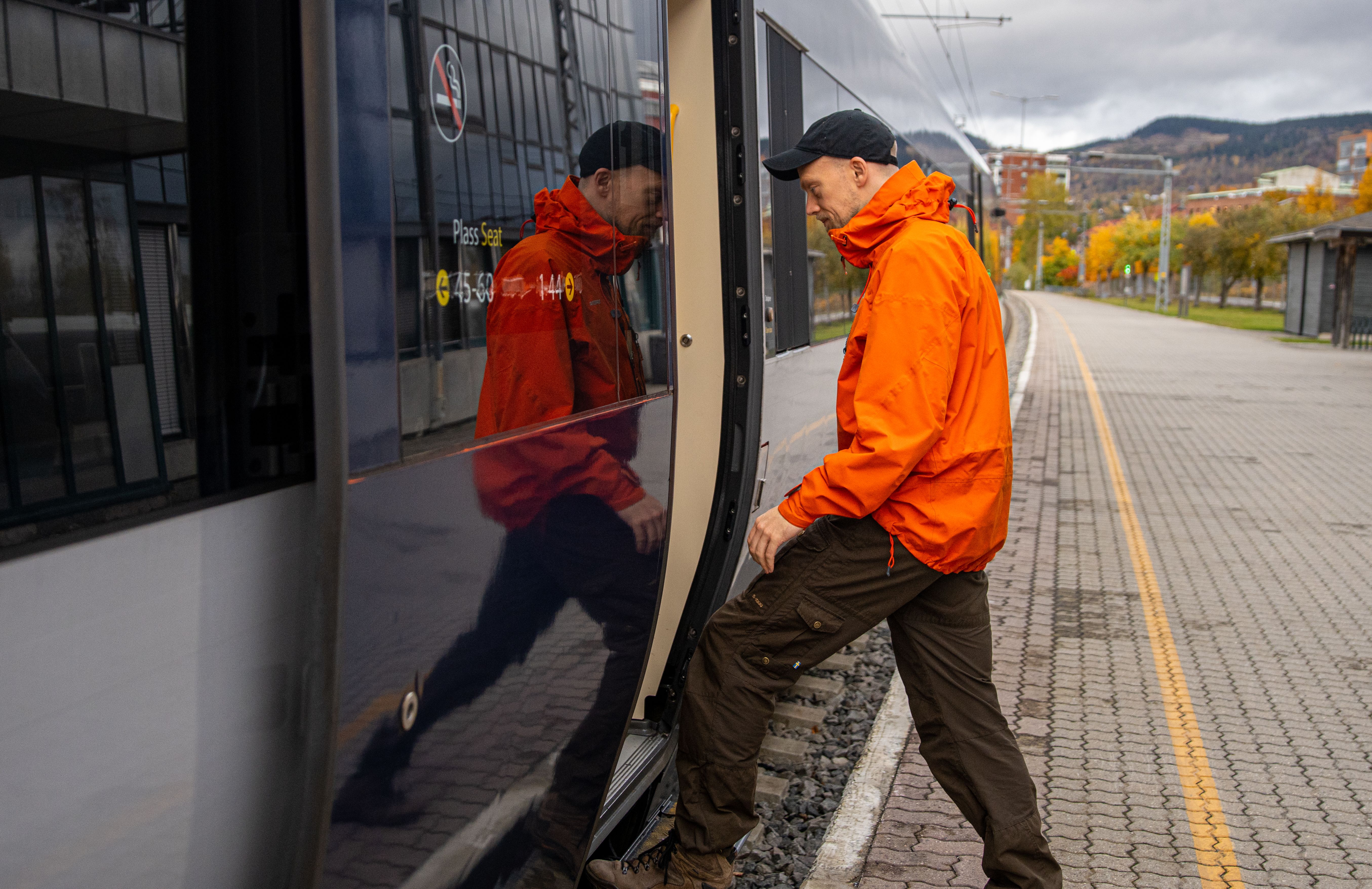 A man getting on board on the Dovre Railway train.