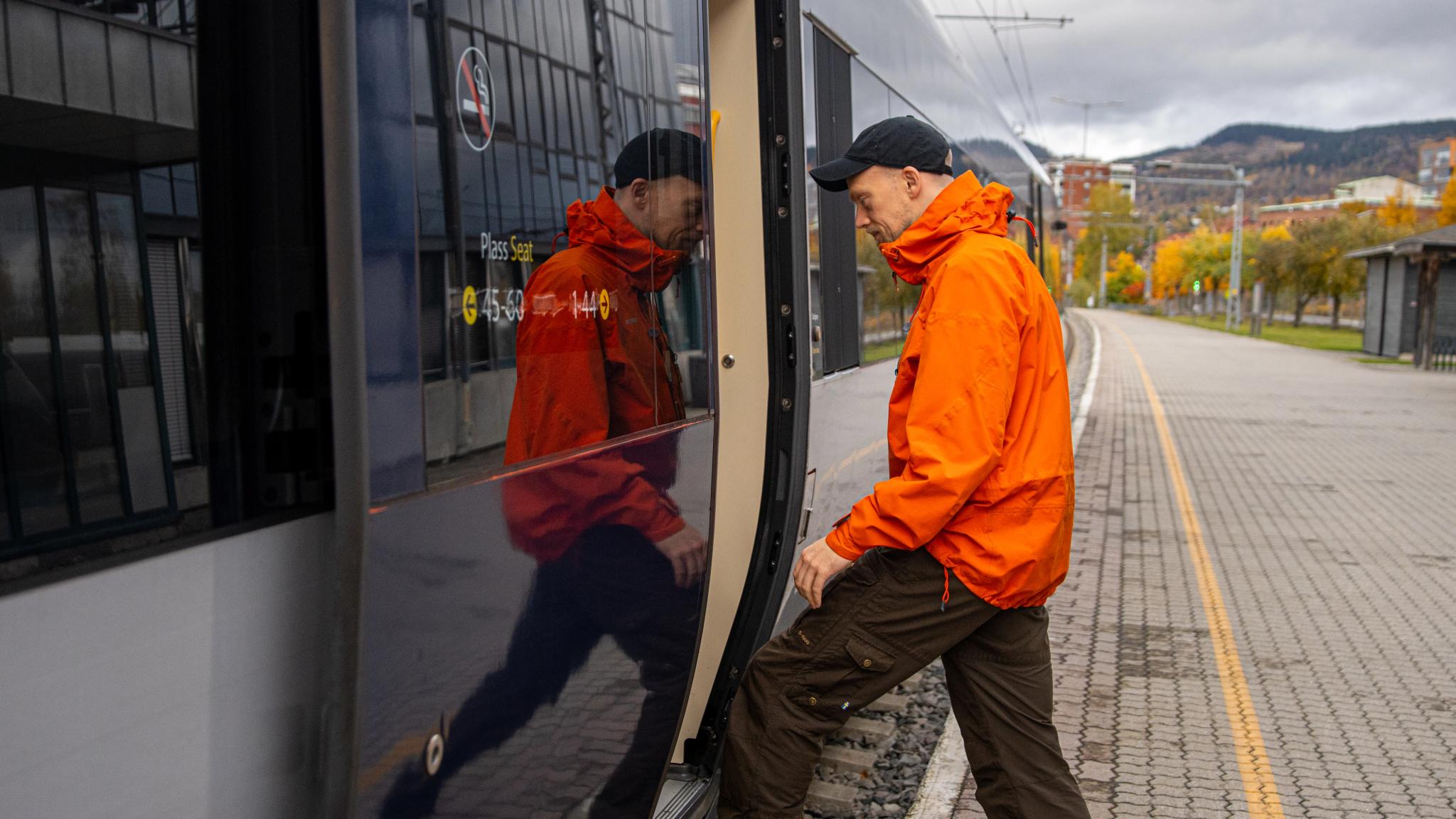 A man getting on board on the Dovre Railway train.