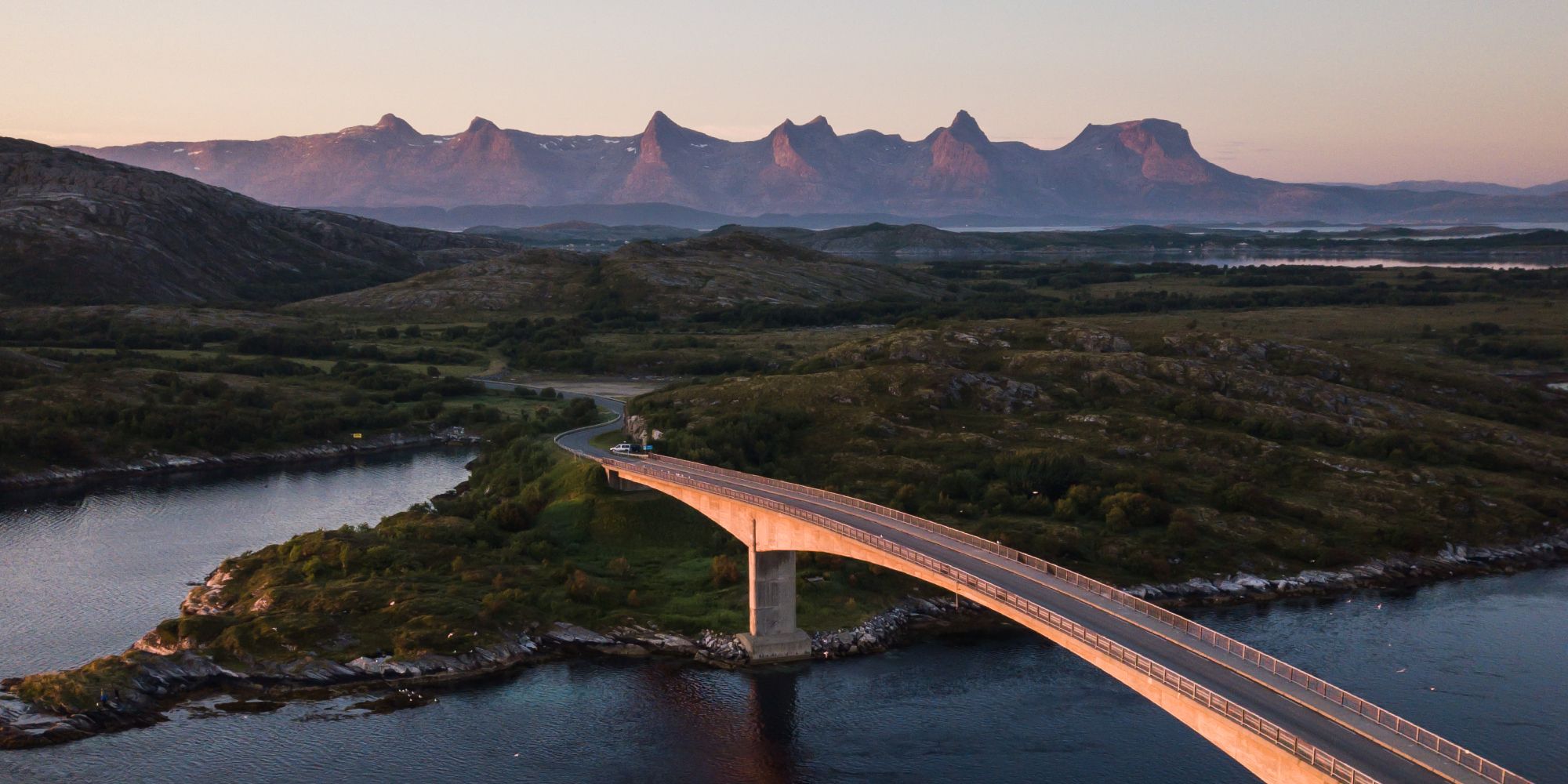 En bro förbinder Herøy med en annan ö i Helgeland, Nord-Norge. I bakgrunden syns bergen De syv søstre (De sju systrarna)