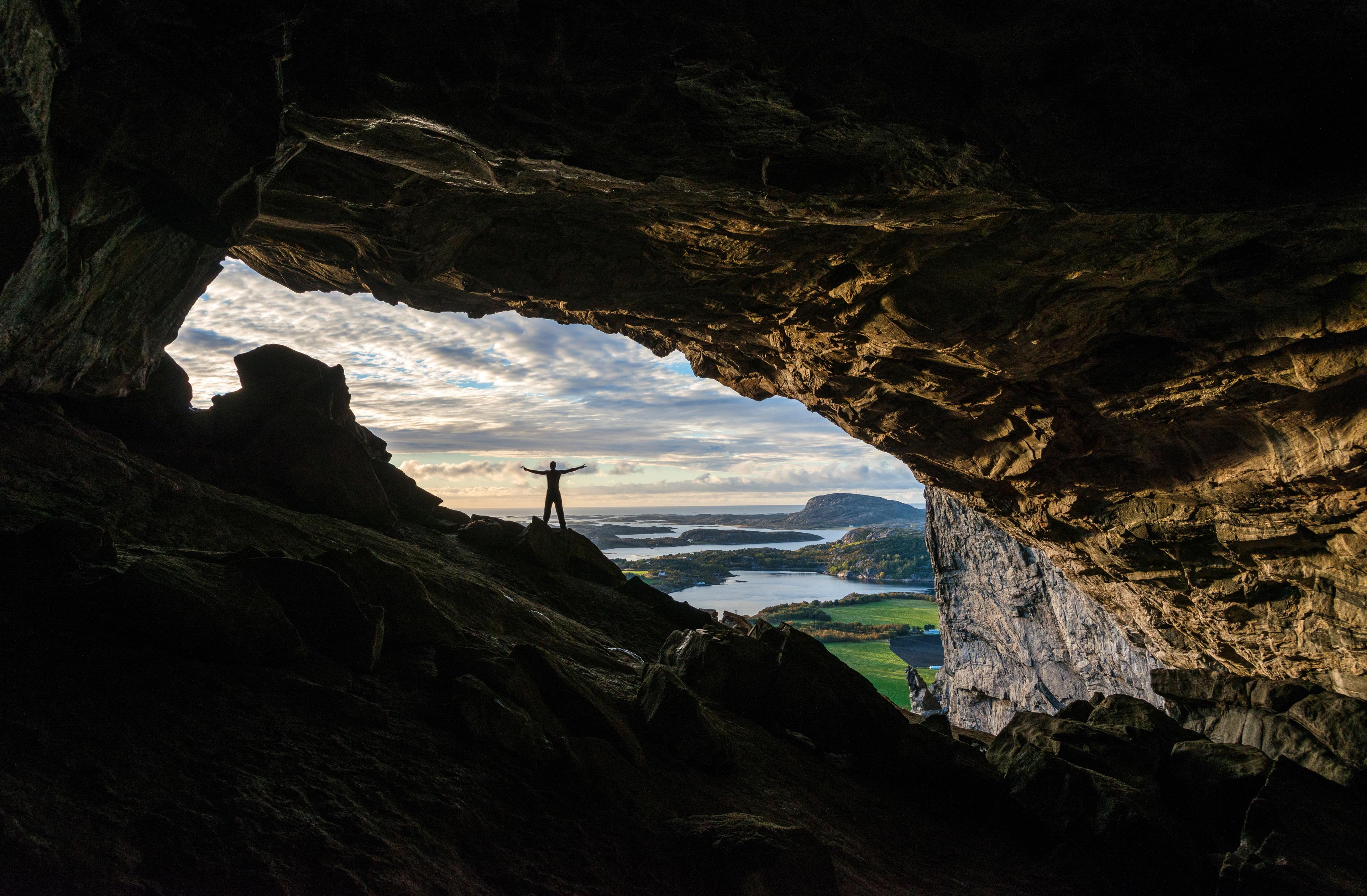 En mann står i åpningen til Hanshelleren hule i Trøndelag