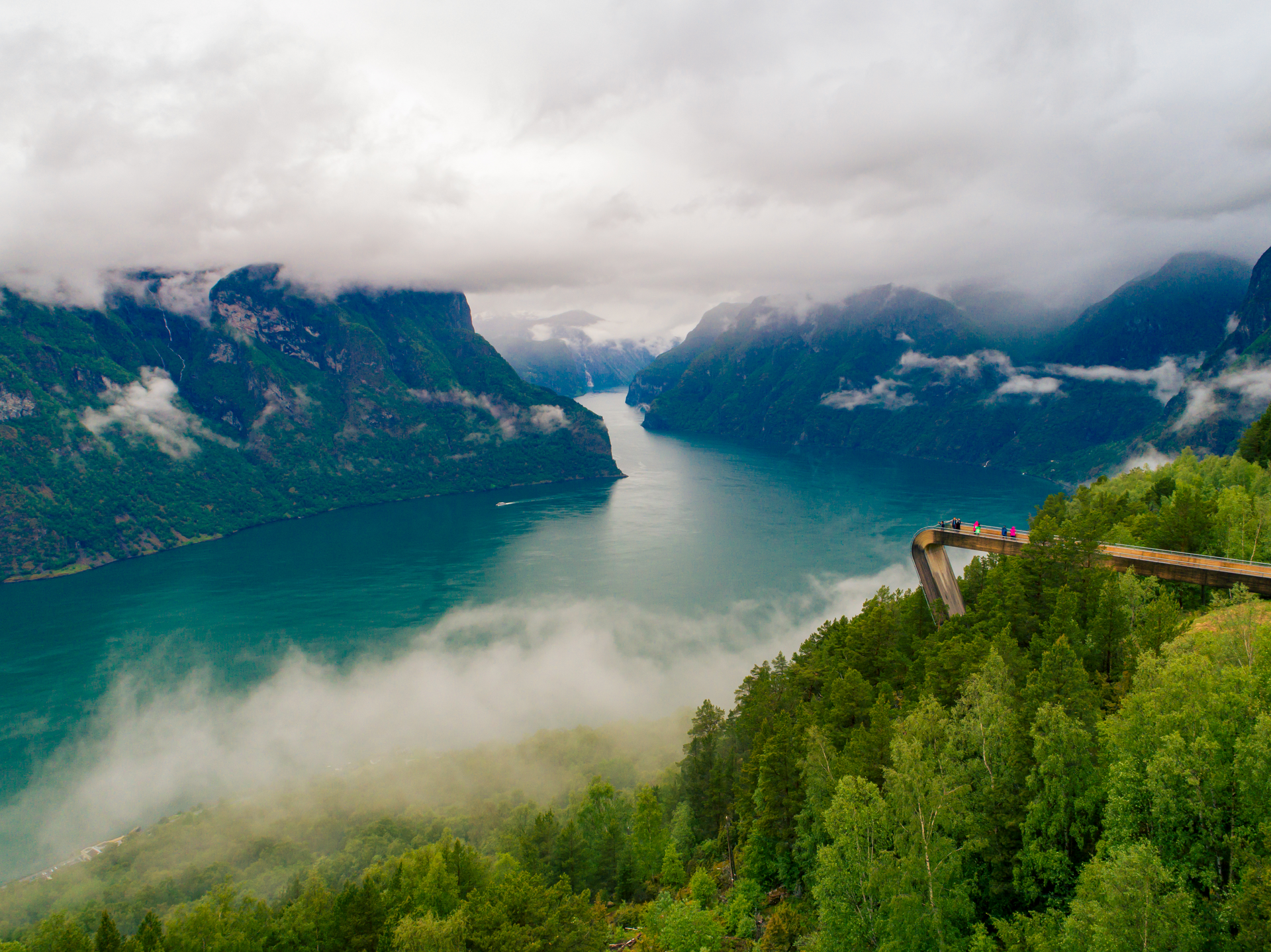 People on a bridge viewpoint overlooking the fjord and snowcapped mountains