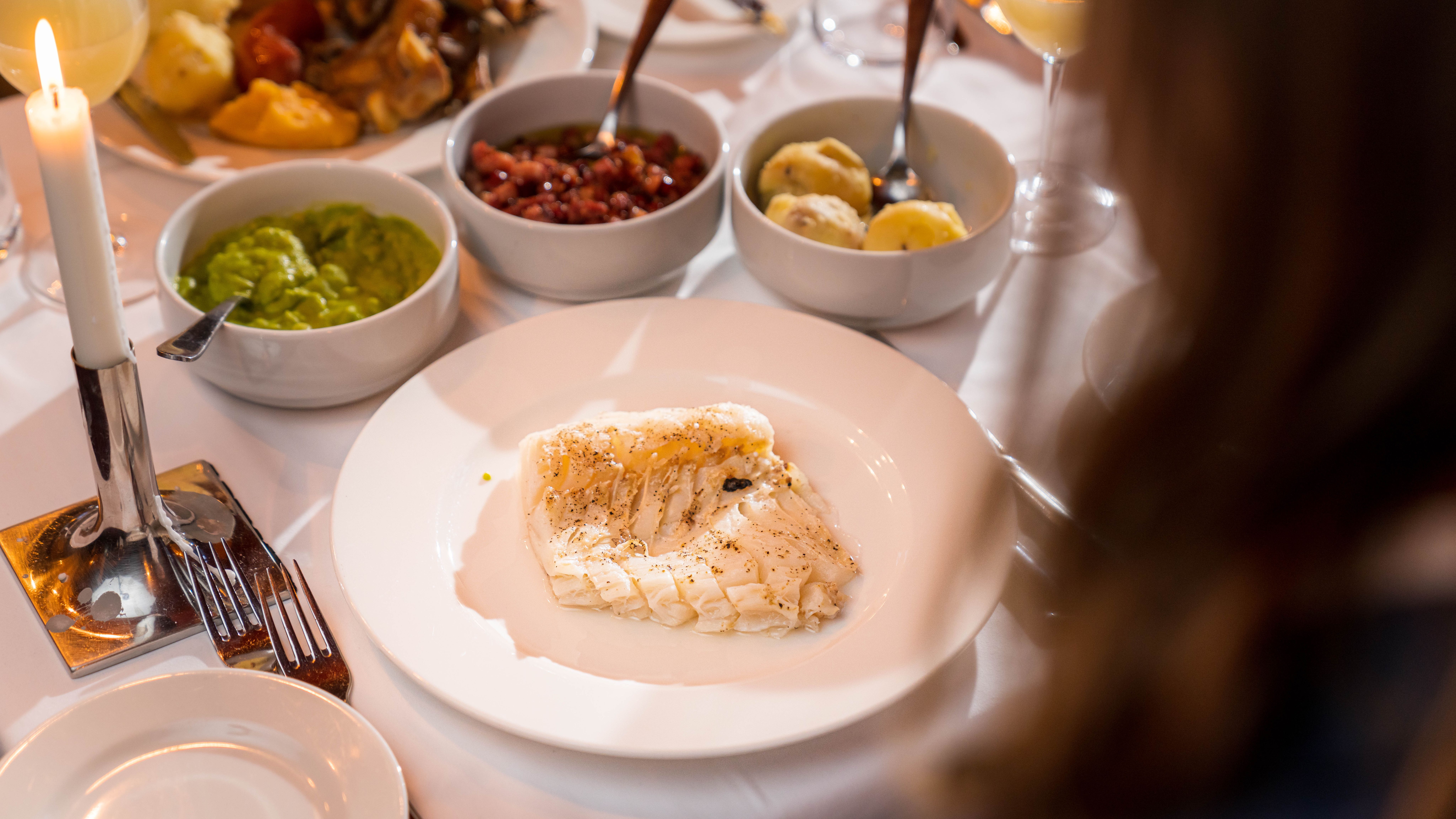 A plate of lutefisk with the most common accessories, pea stew, bacon, and potatoes