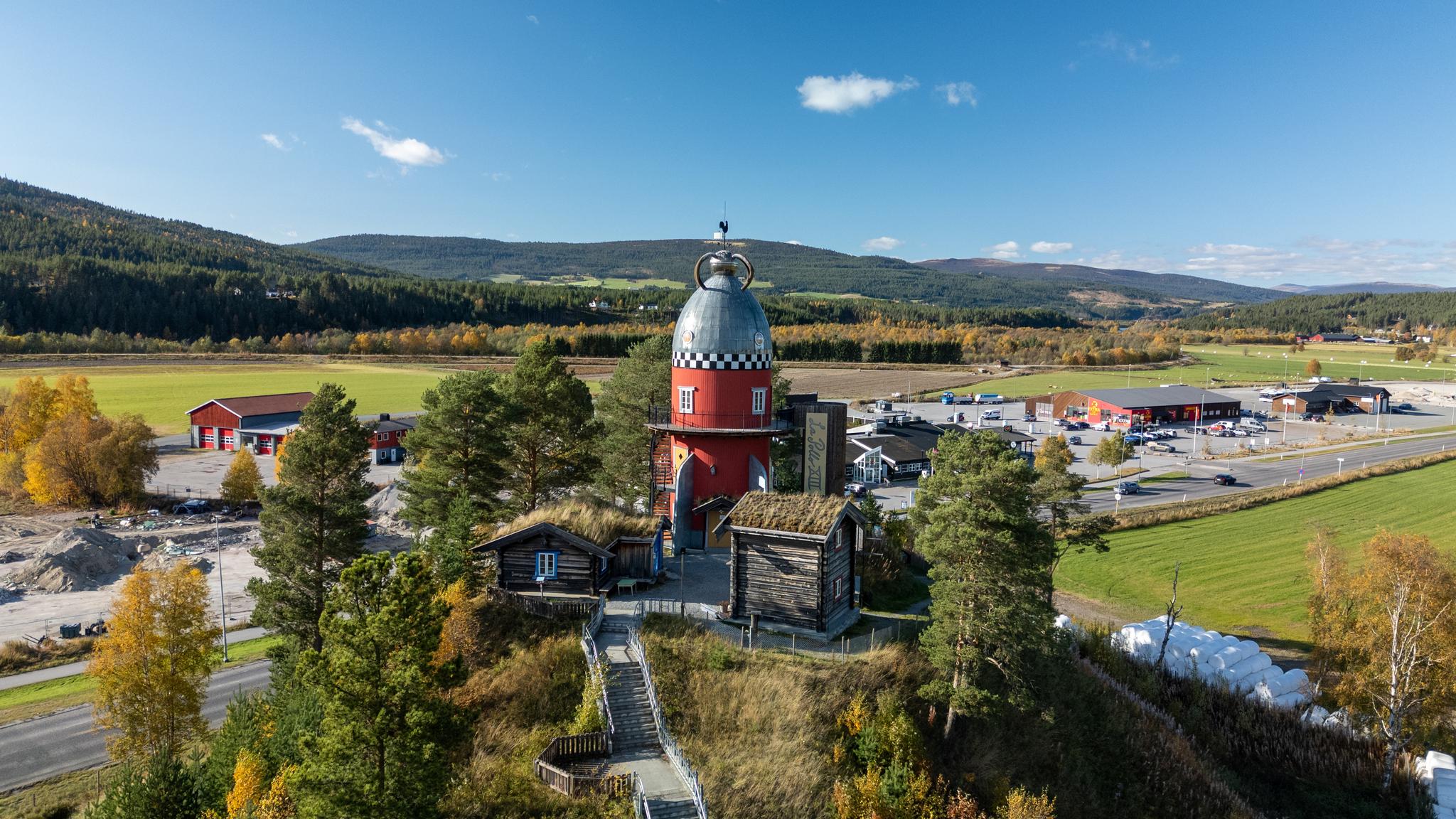 A colourful rocket ship and several wooden houses on a hill.