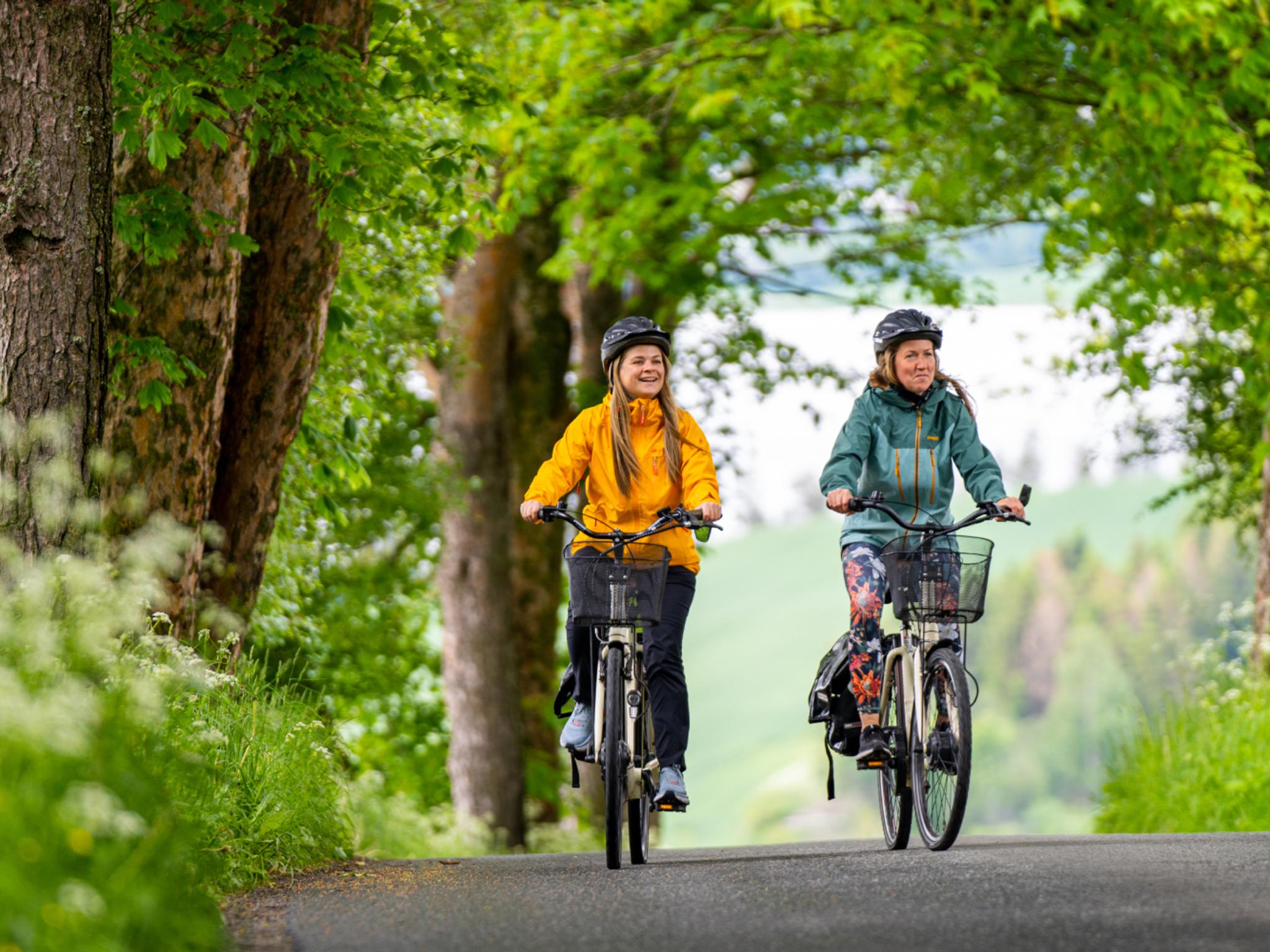 Two woman cycling among flowerfields at The Golden Road, Inderøy