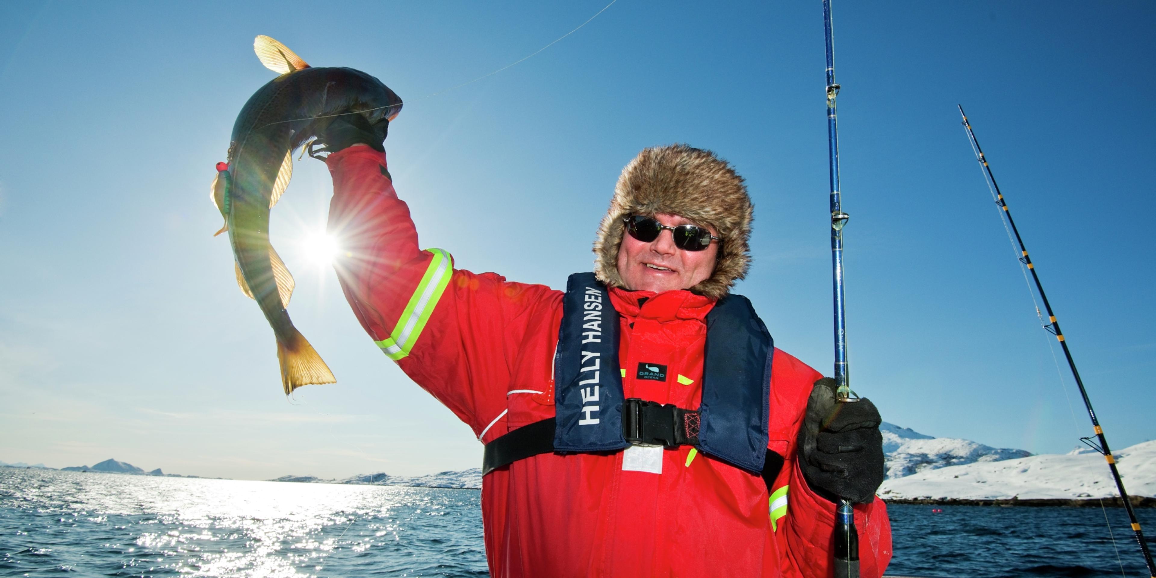 A man who has caught a fish in Austnesfjorden in Lofoten in Northern Norway
