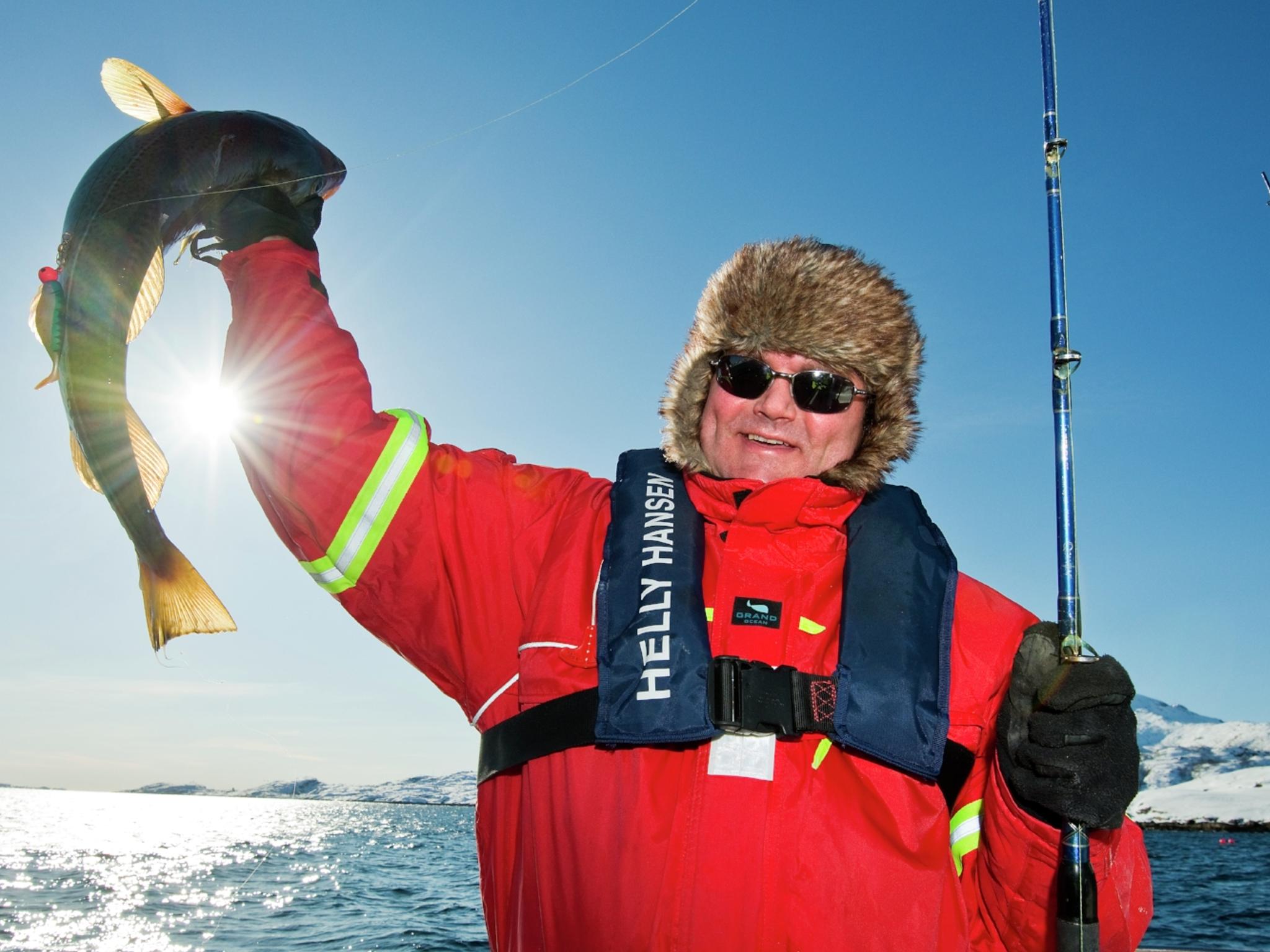 A man who has caught a fish in Austnesfjorden in Lofoten in Northern Norway