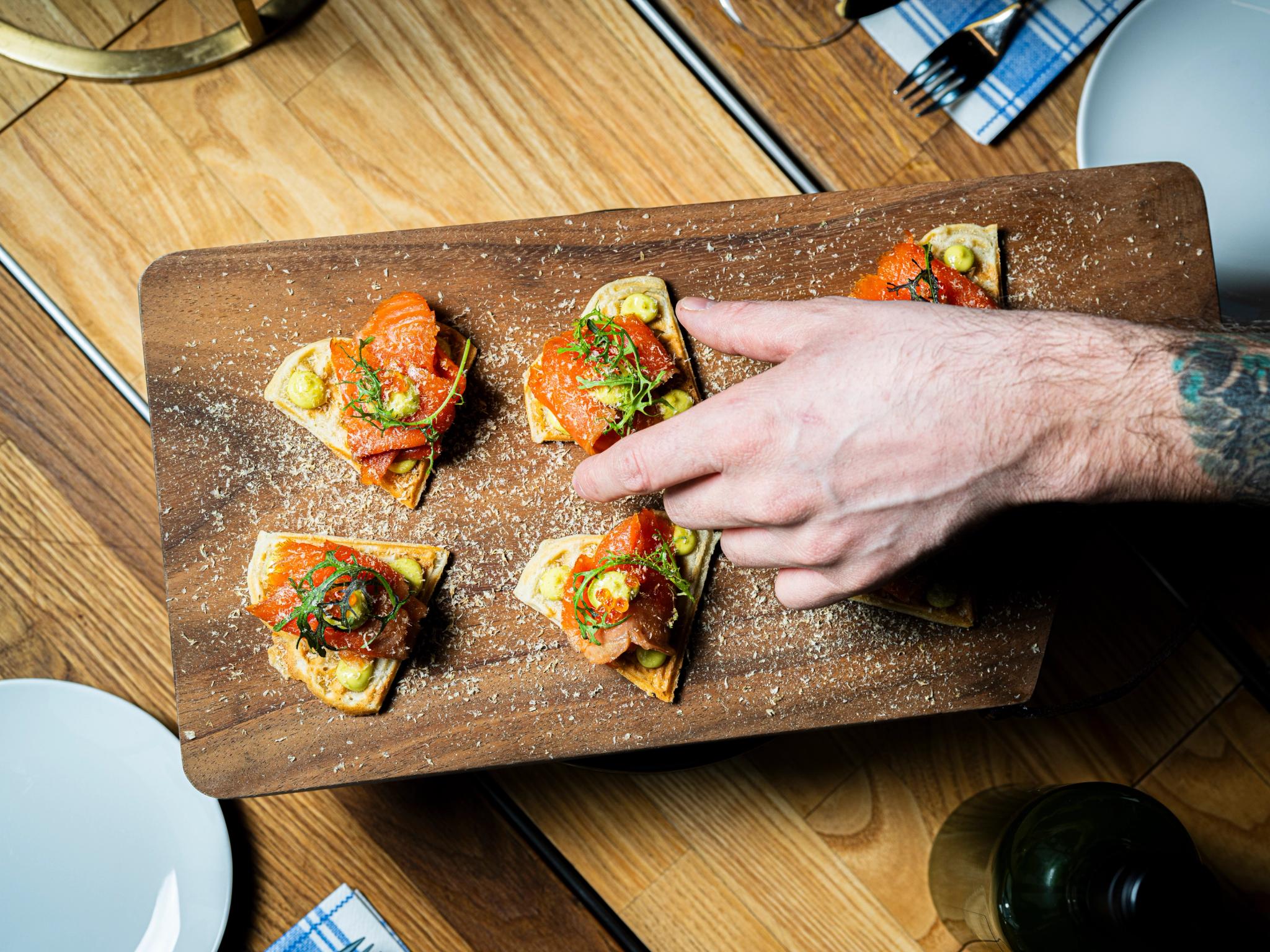 A hand grabbing a salmon snack.