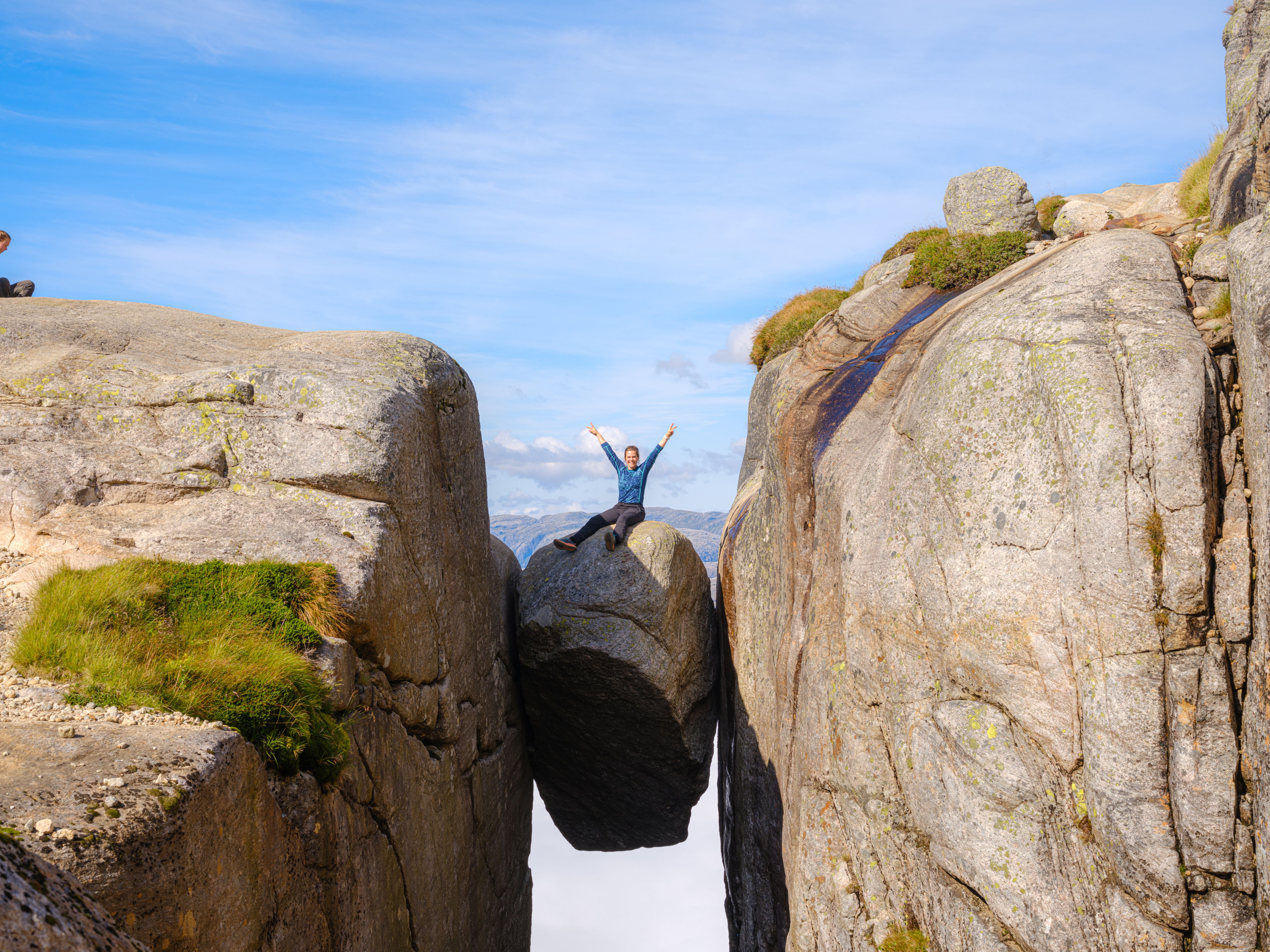 Kvinne sitter på Kjeragbolten i Lysefjord, Vestlandet