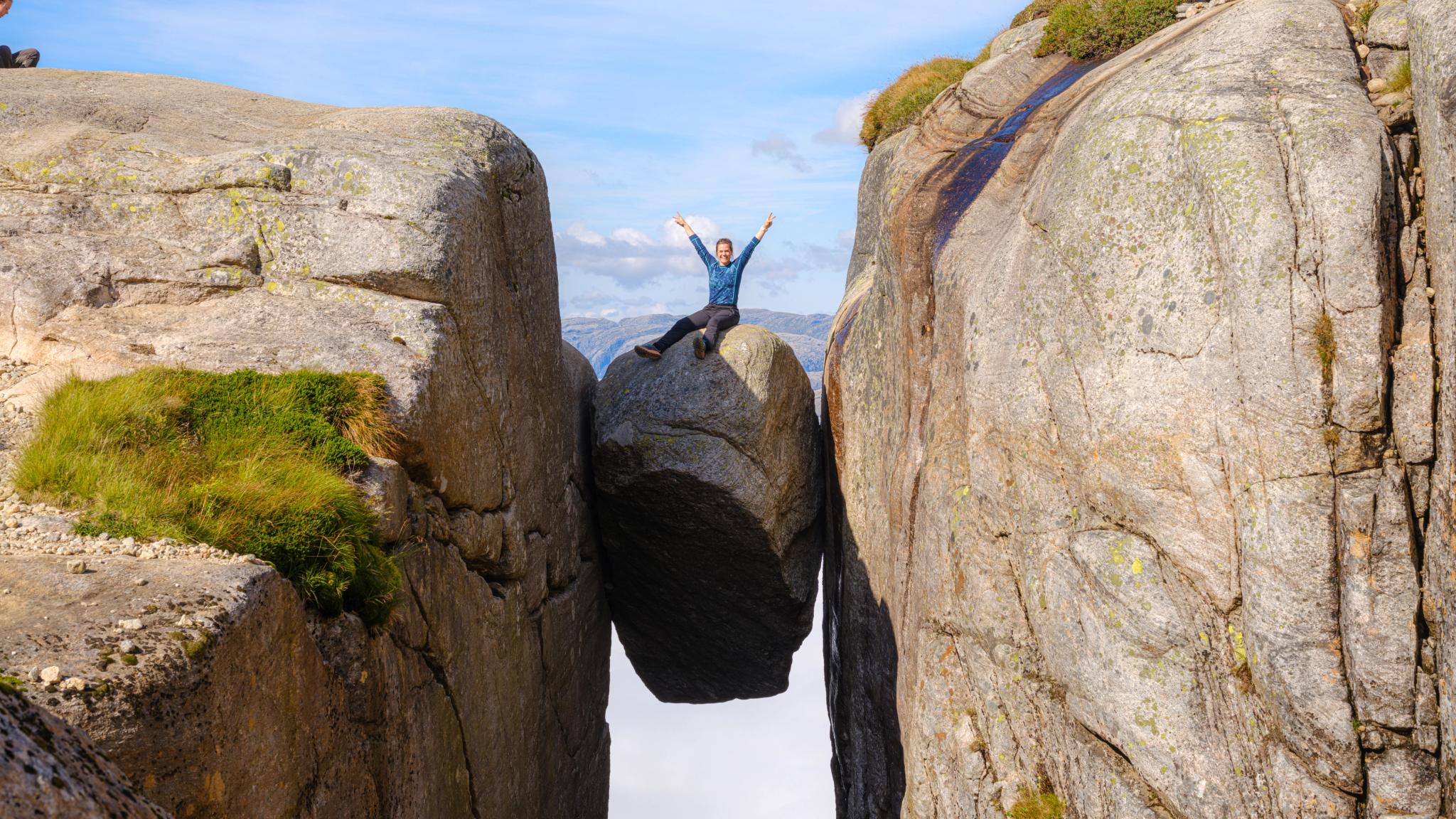 Kvinne sitter på Kjeragbolten i Lysefjord, Vestlandet