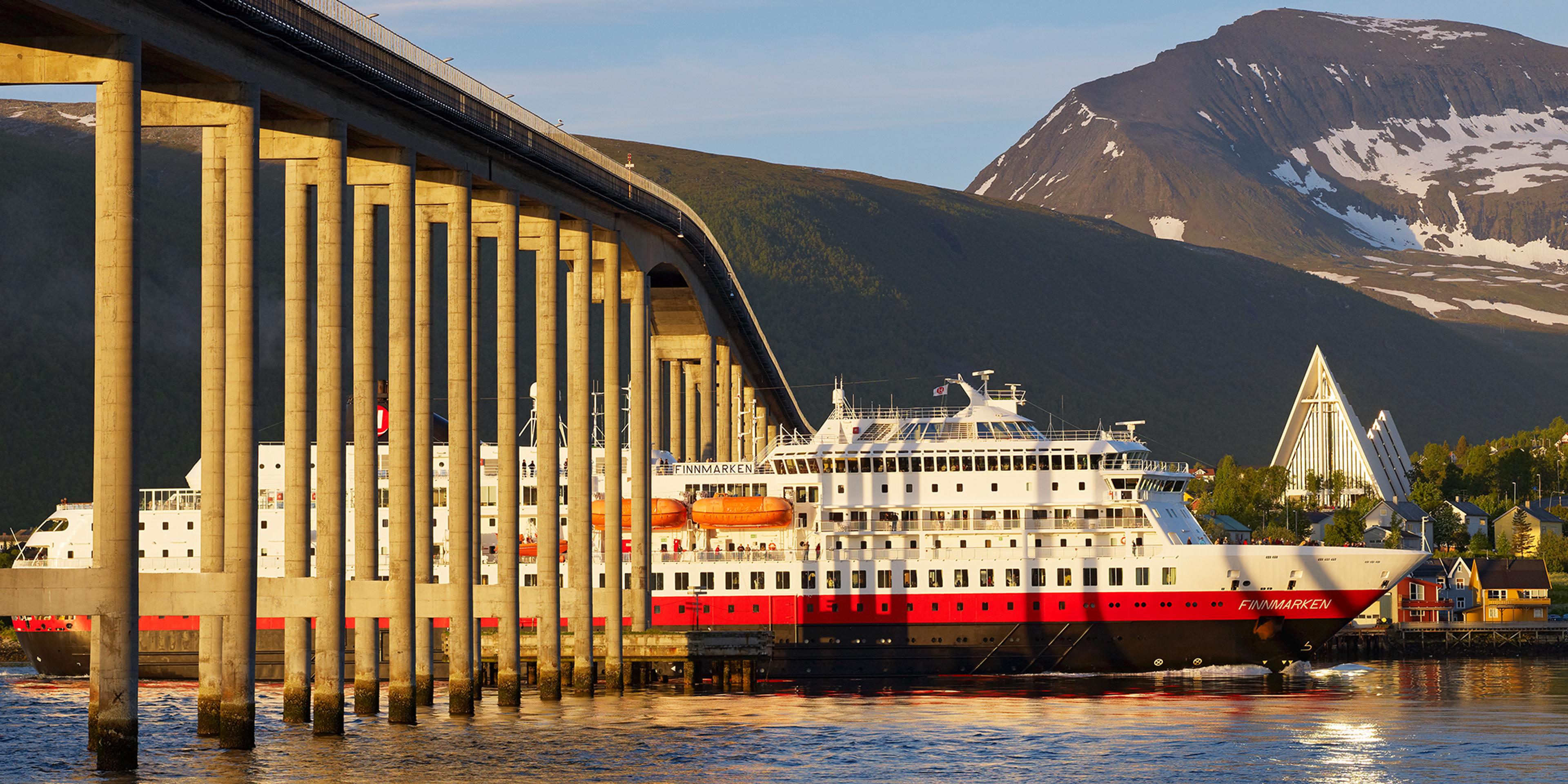 Hurtigruten sailing under a bridge in Tromsø