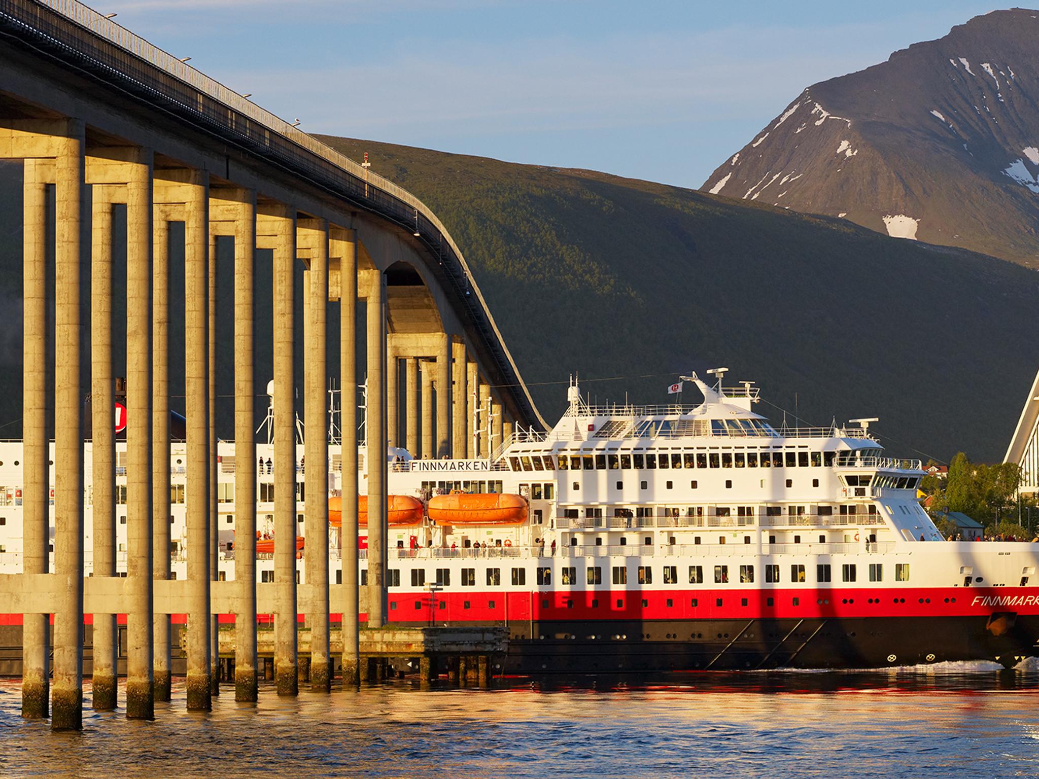 Hurtigruten sailing under a bridge in Tromsø