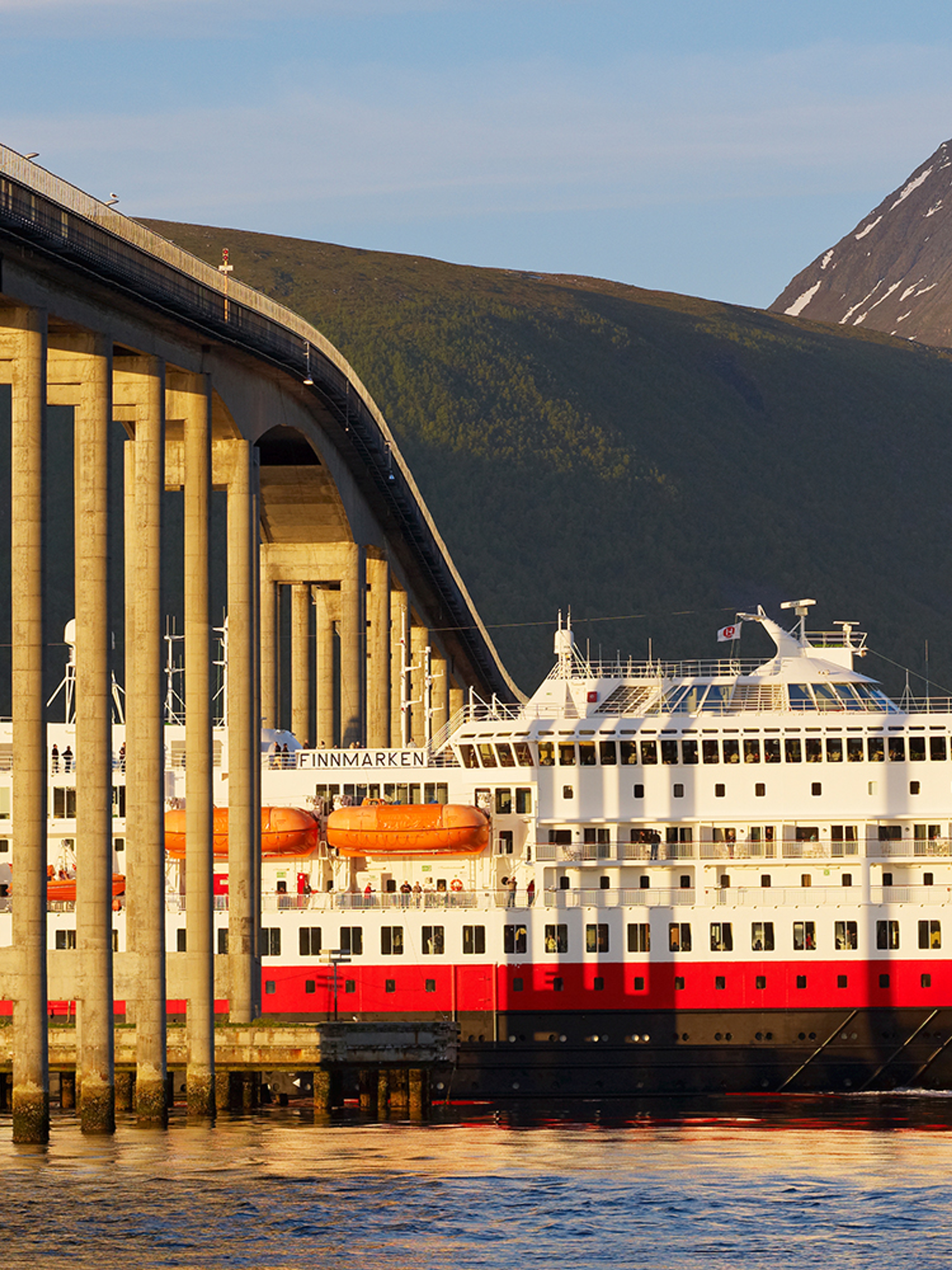 Hurtigruten seiler under en bro i Tromsø