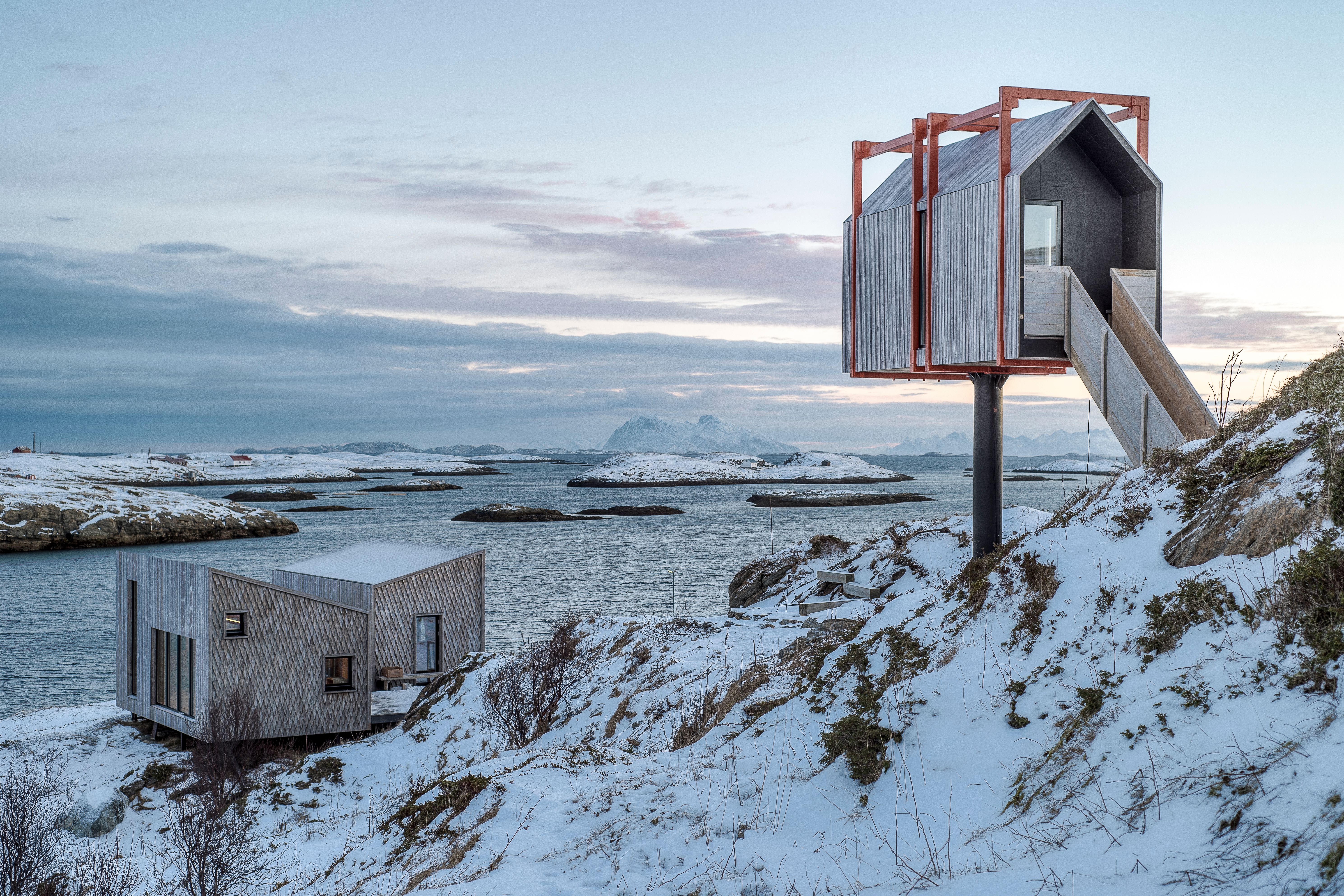 Varius modern wooden cabins in a lightly snow covered landscpe.
