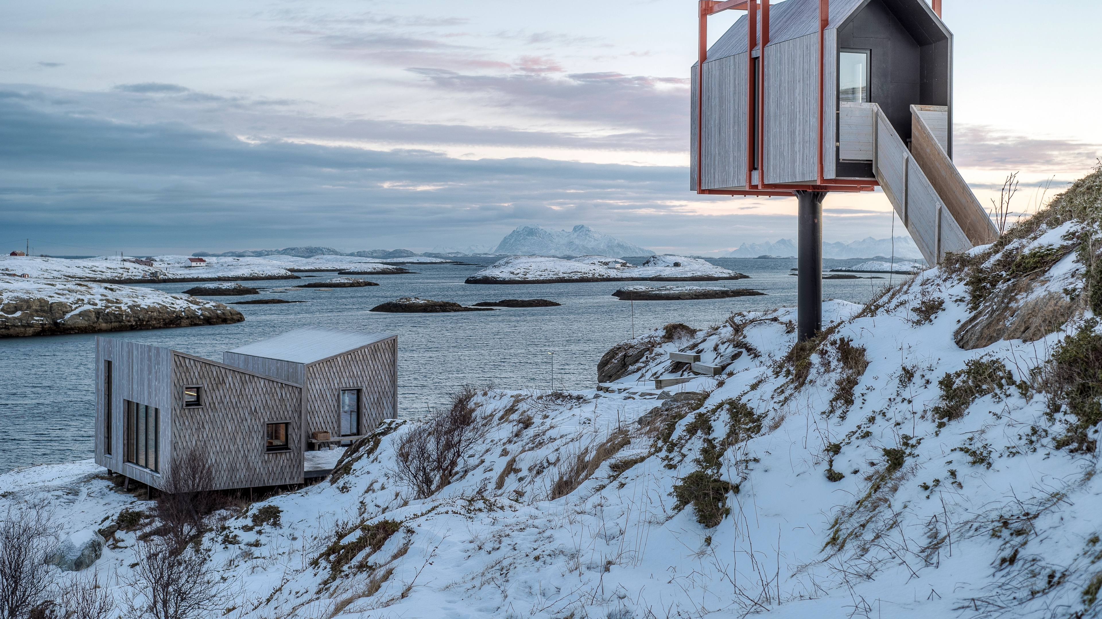 Varius modern wooden cabins in a lightly snow covered landscpe.