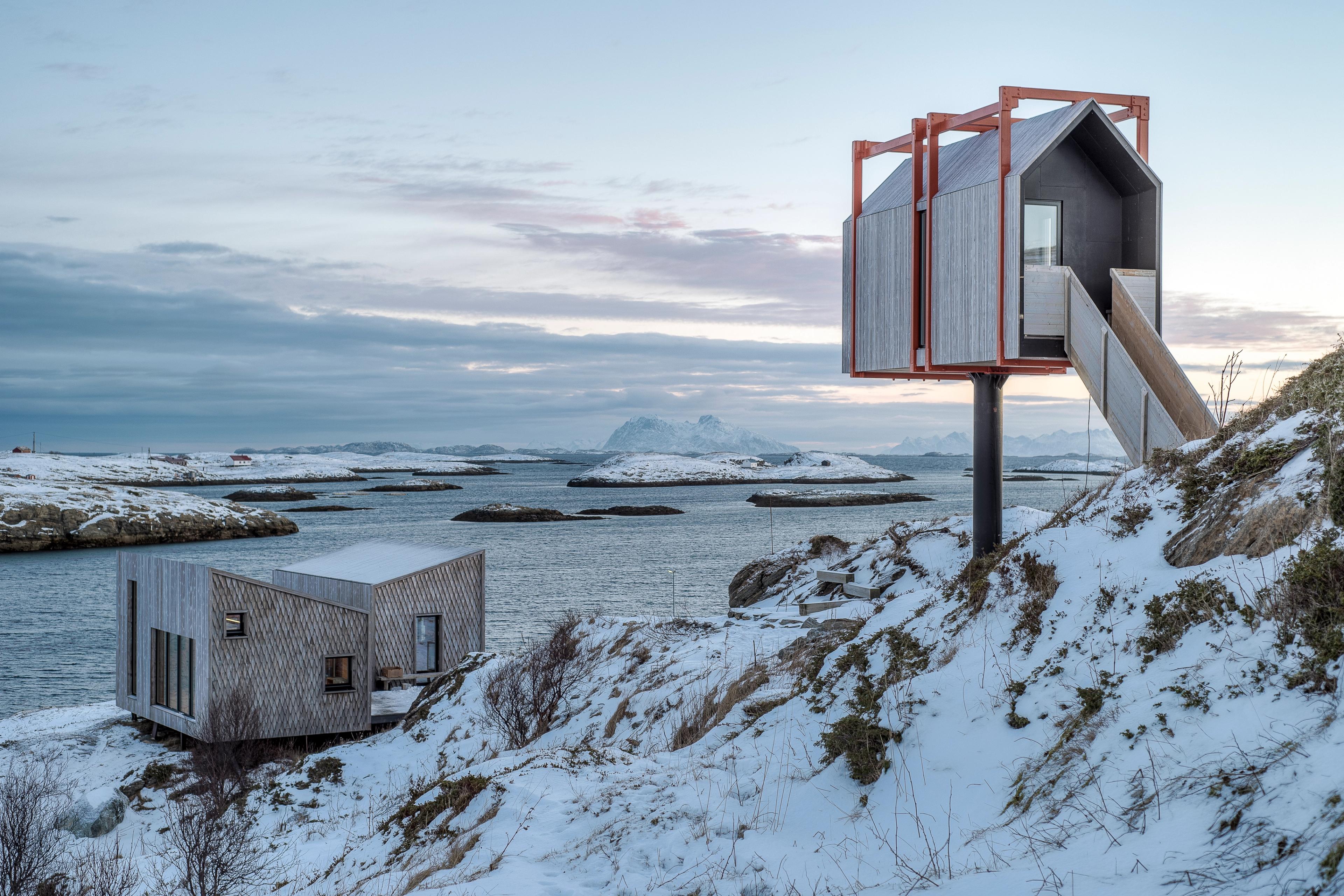 Varius modern wooden cabins in a lightly snow covered landscpe.