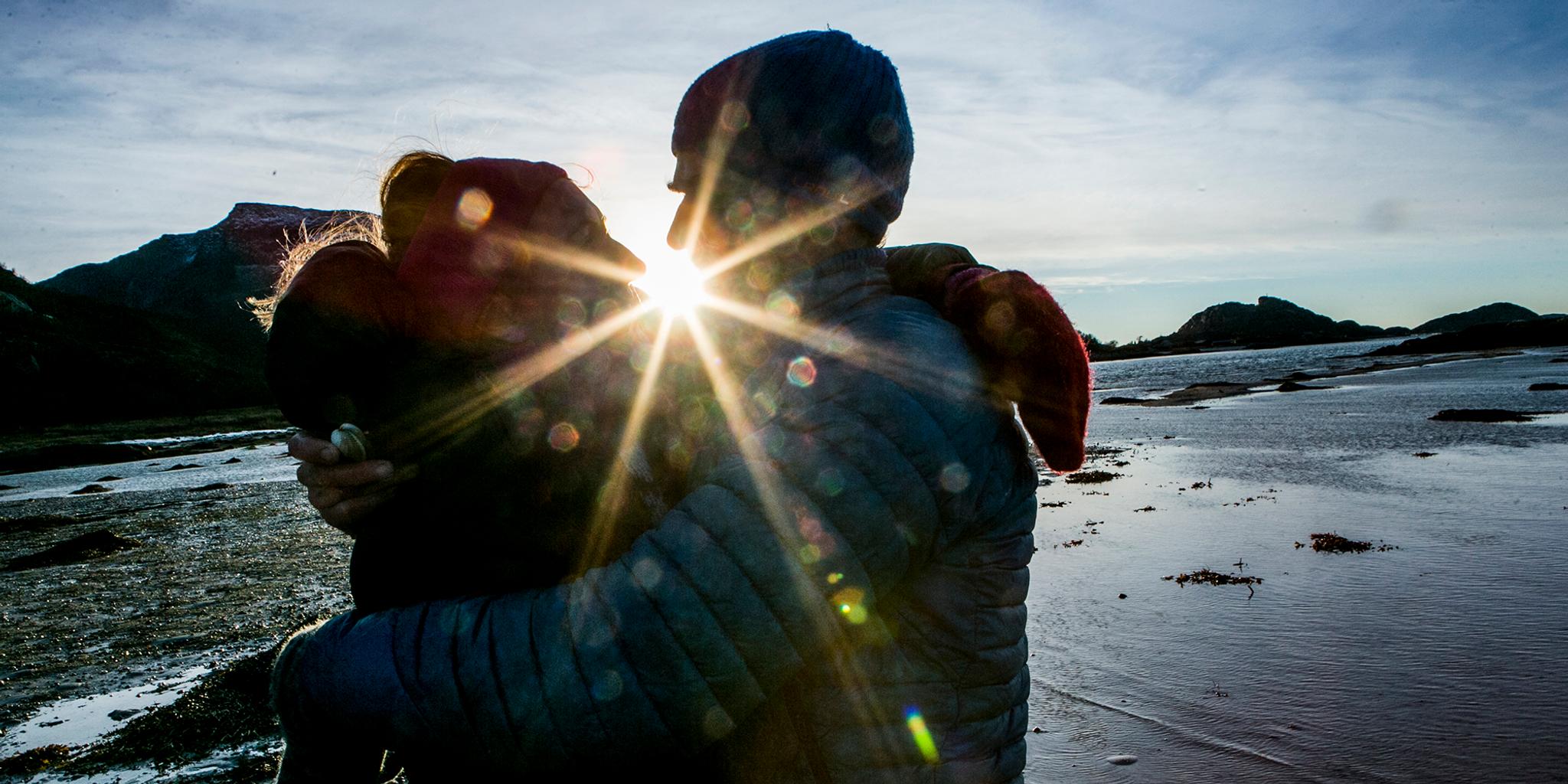 Rays of sunlight between a man and a woman kissing in Steigen in Nordland, Northern Norway