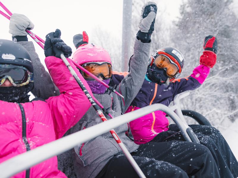 Three happy girls sitting in a ski lift in Geilo ski resort, Eastern Norway