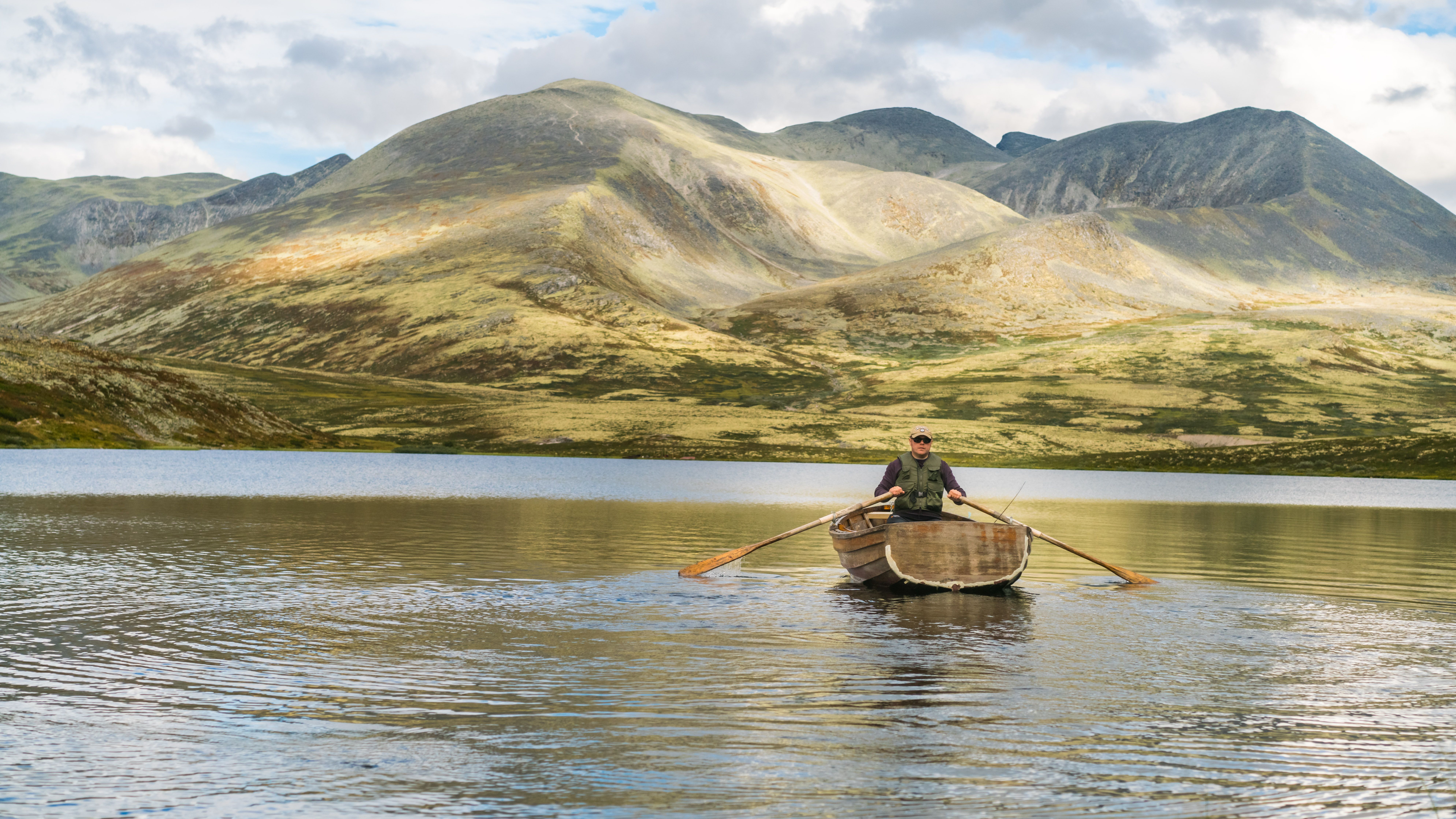 Man rowing a wooden boat on a lake in Rondane, Eastern Norway.