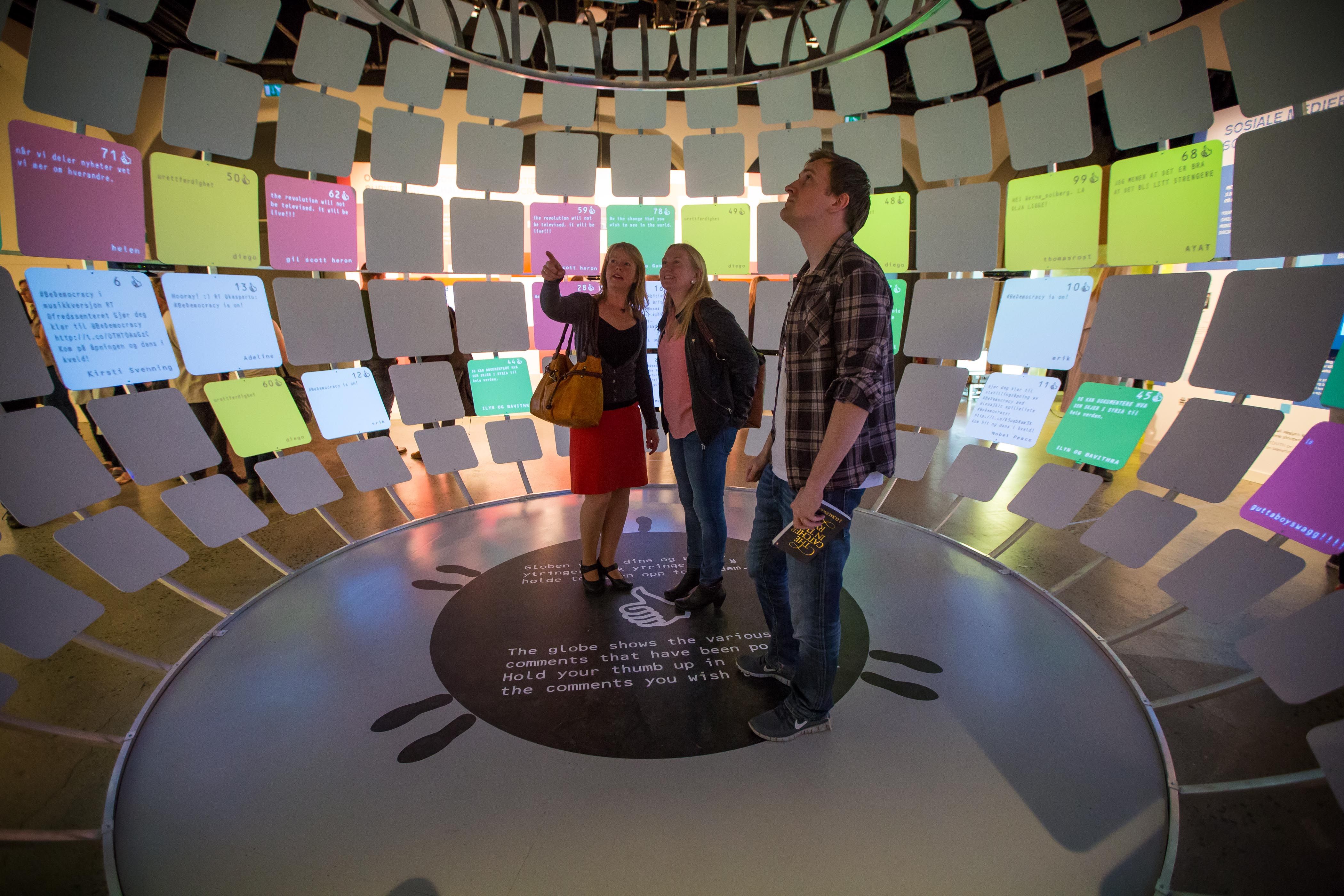 Three people enjoying an exhibition at the Nobel Peace Center in Oslo, Norway