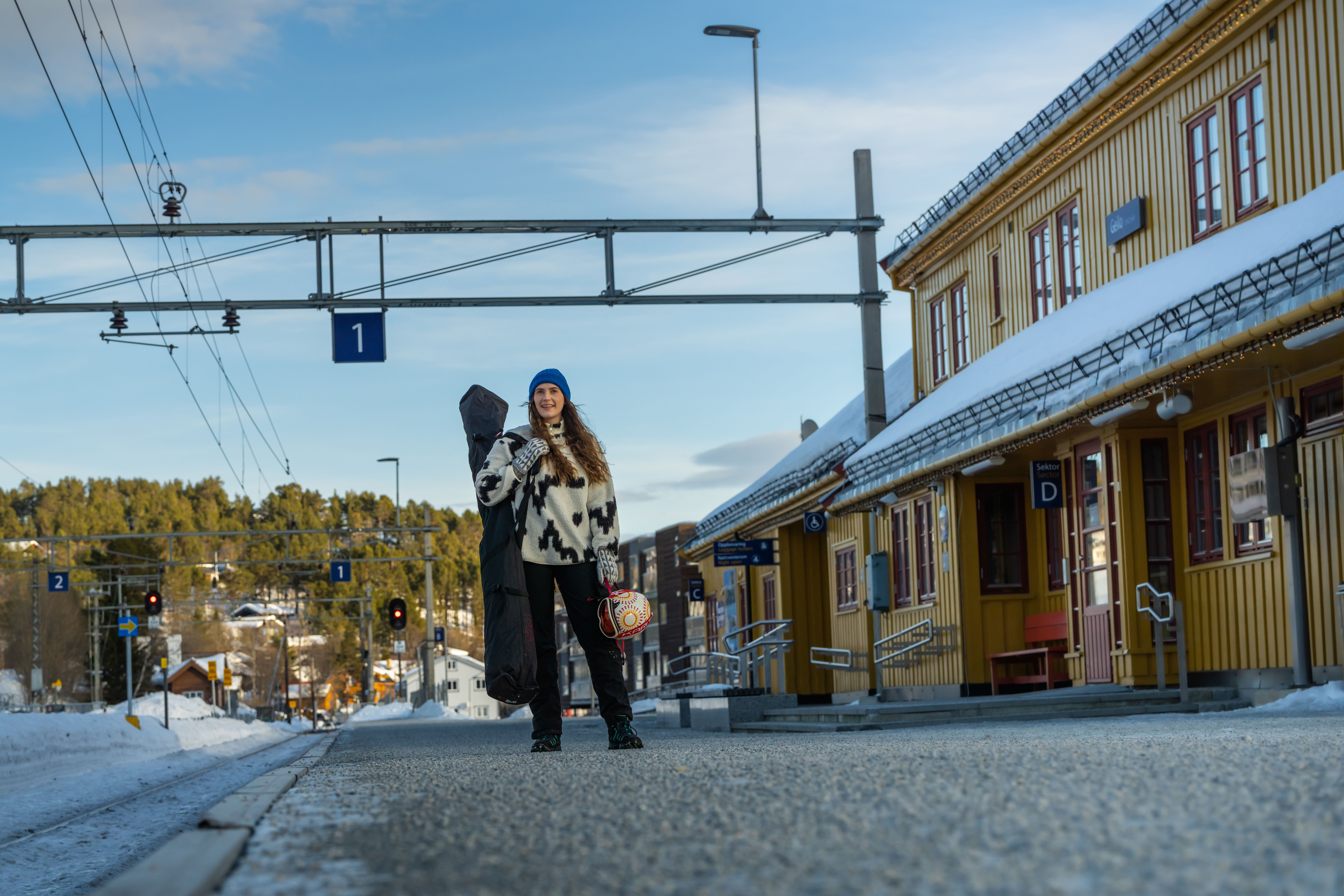 Woman in ski attire waiting on the railway platform for her train to the slopes
