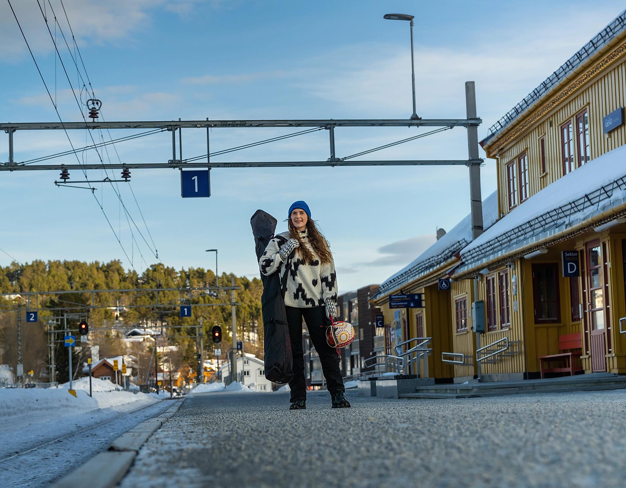 Woman in ski attire waiting on the railway platform for her train to the slopes