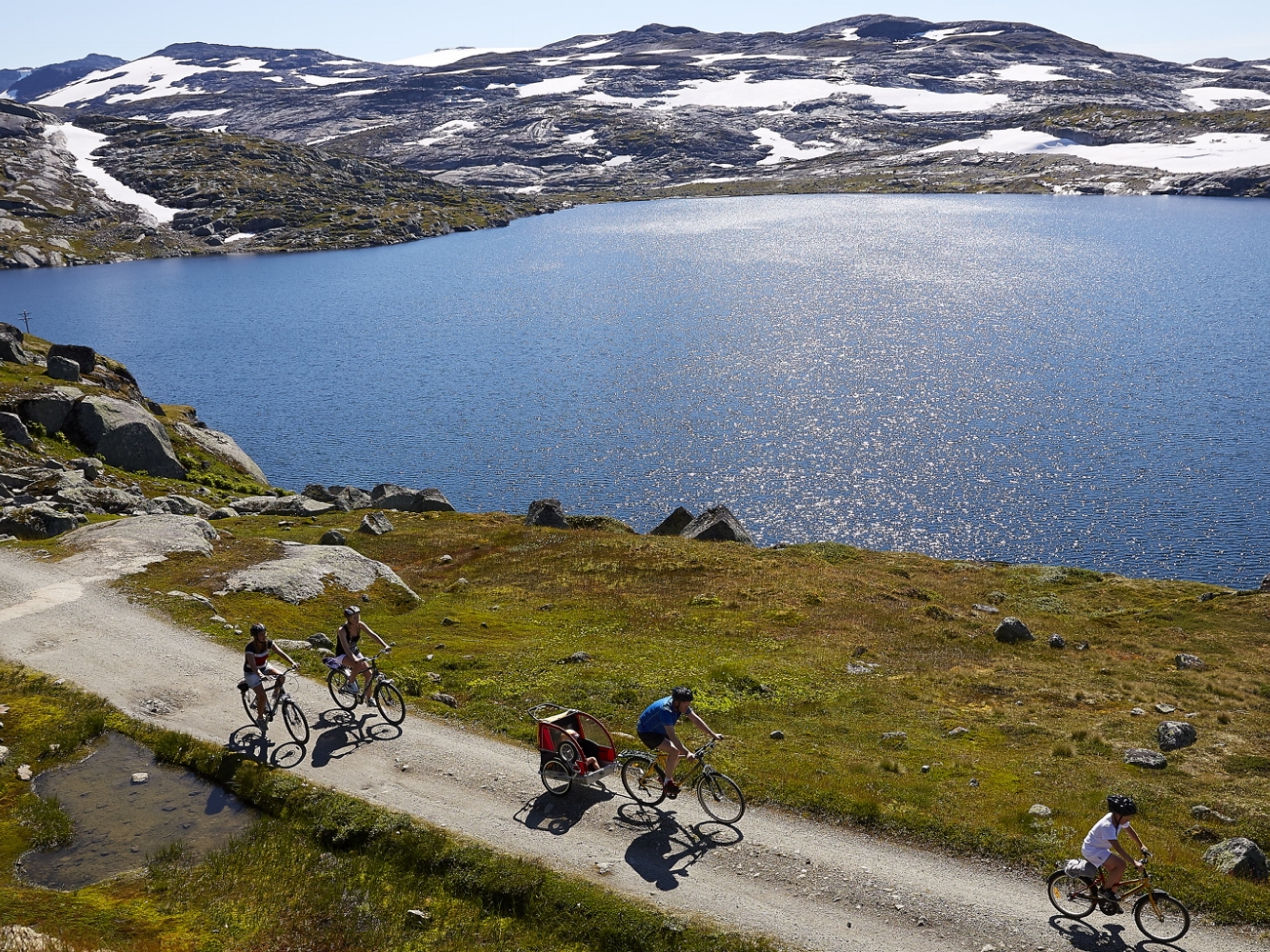 Eine Gruppe, die entlang eines Sees bei Rallarvegen in Ostnorwegen radelt