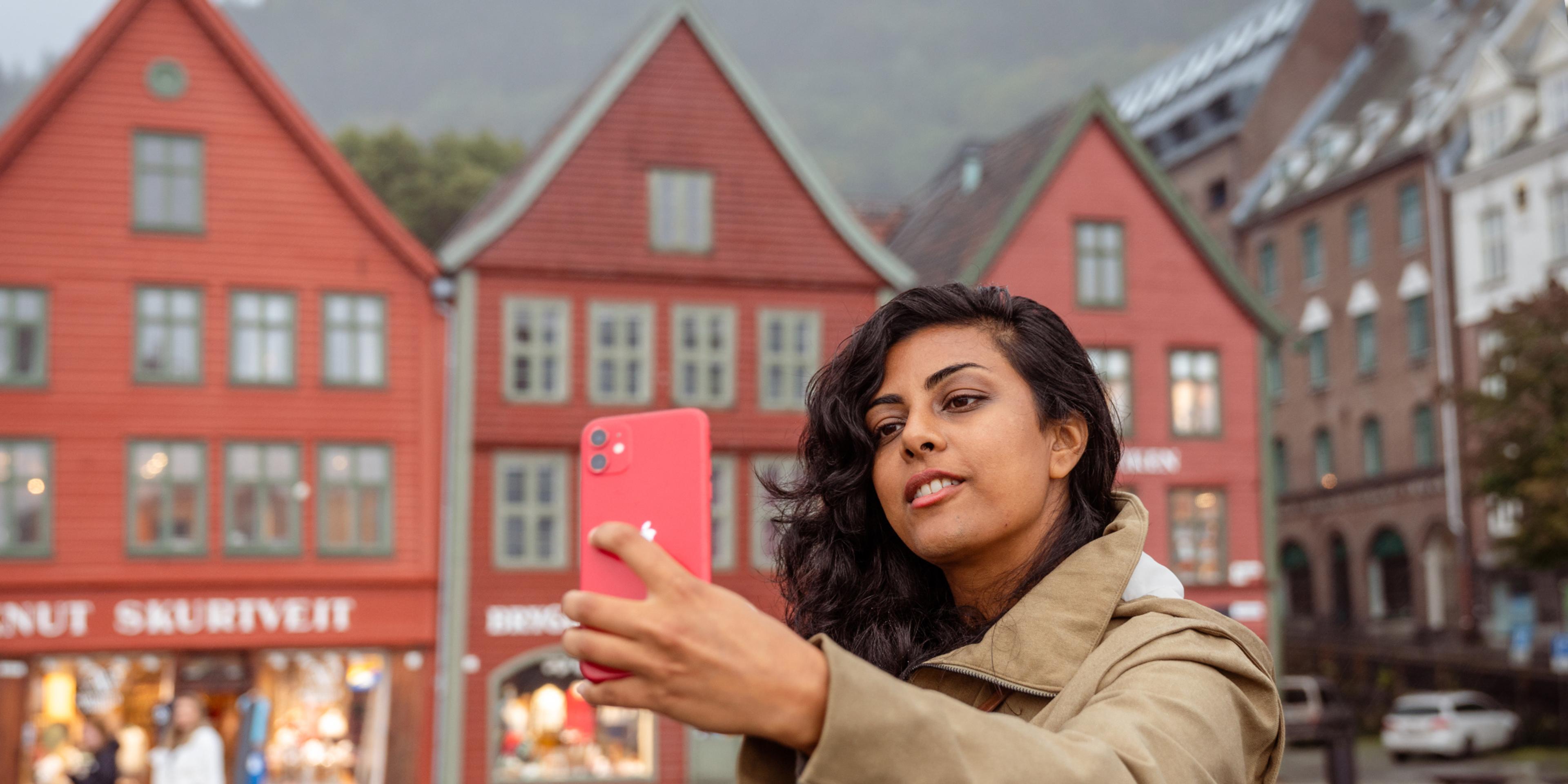A woman on a walking tour taking a selfie at Bryggen in Bergen, Fjord Norway