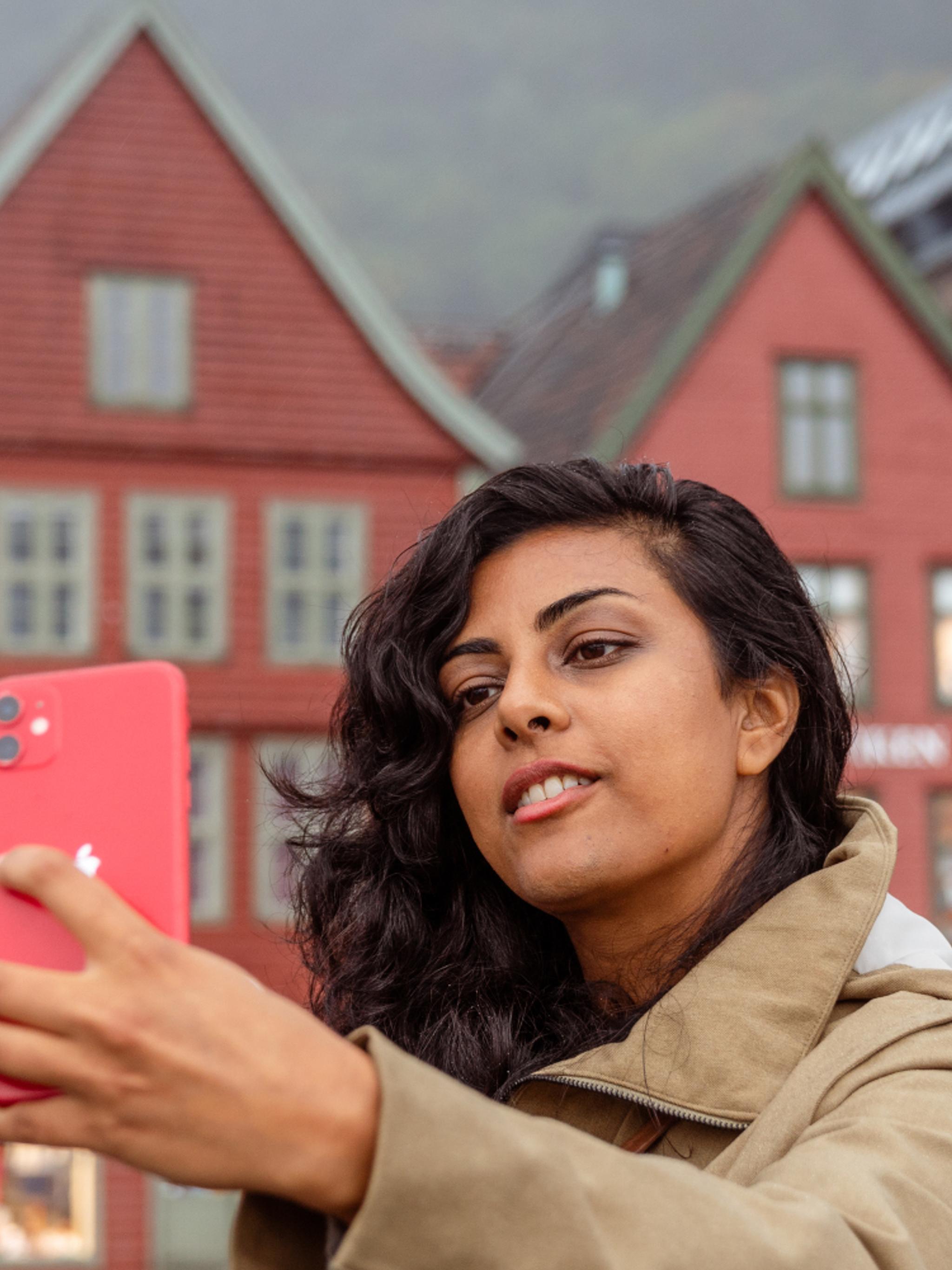 A woman on a walking tour taking a selfie at Bryggen in Bergen, Fjord Norway