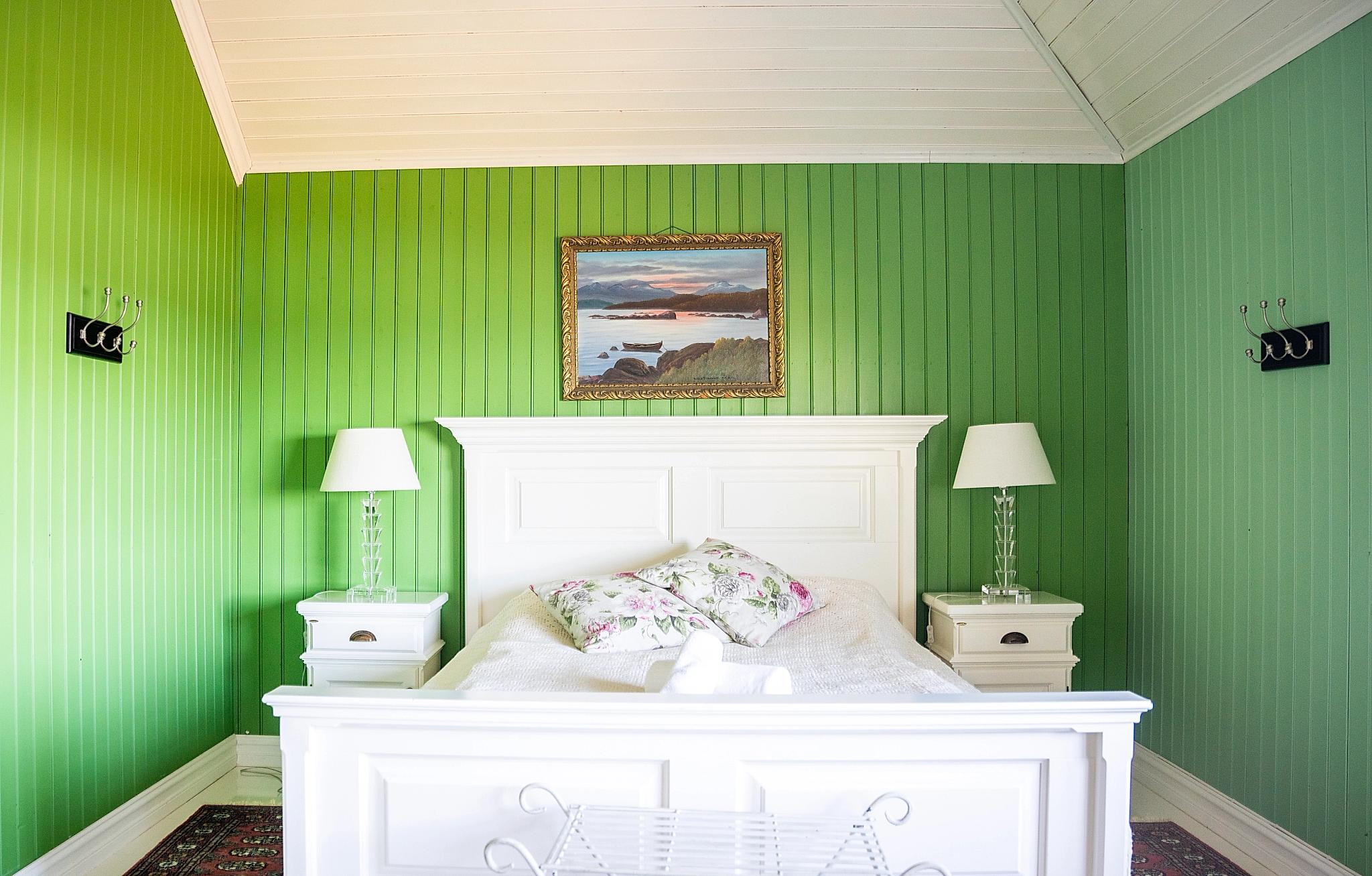 White bed in green hotel room.