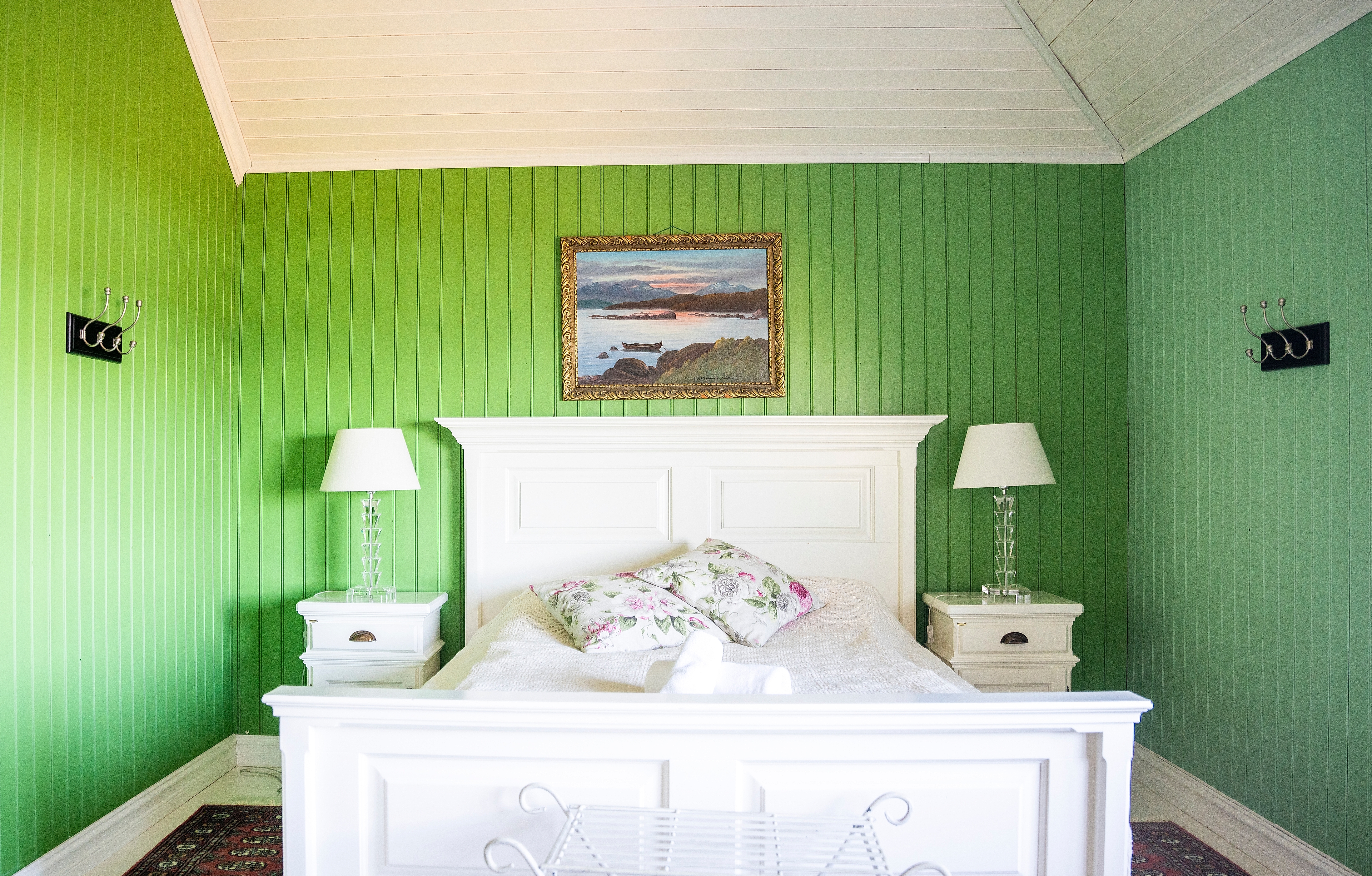 White bed in green hotel room.