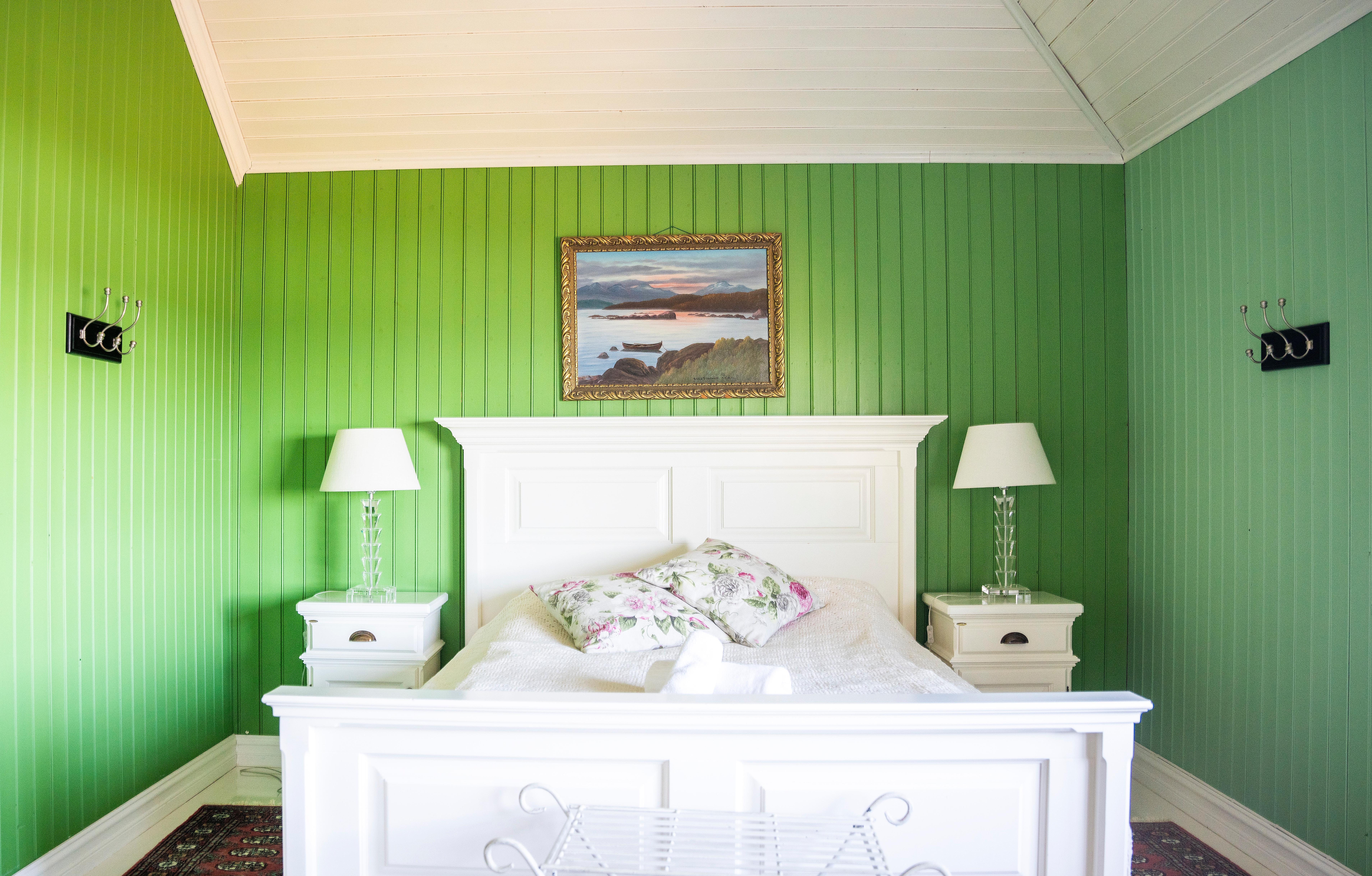 White bed in green hotel room.